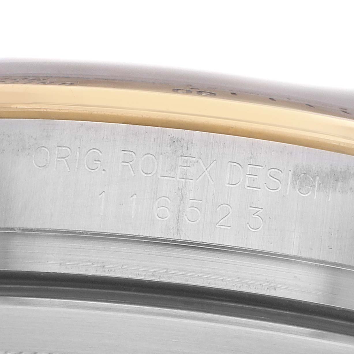 The image shows a close-up of the side of a Rolex Daytona 116523 Men's Steel and Gold (two tone) White Dial watch, focusing on the engraved model number and "Orig. Rolex Design" text.