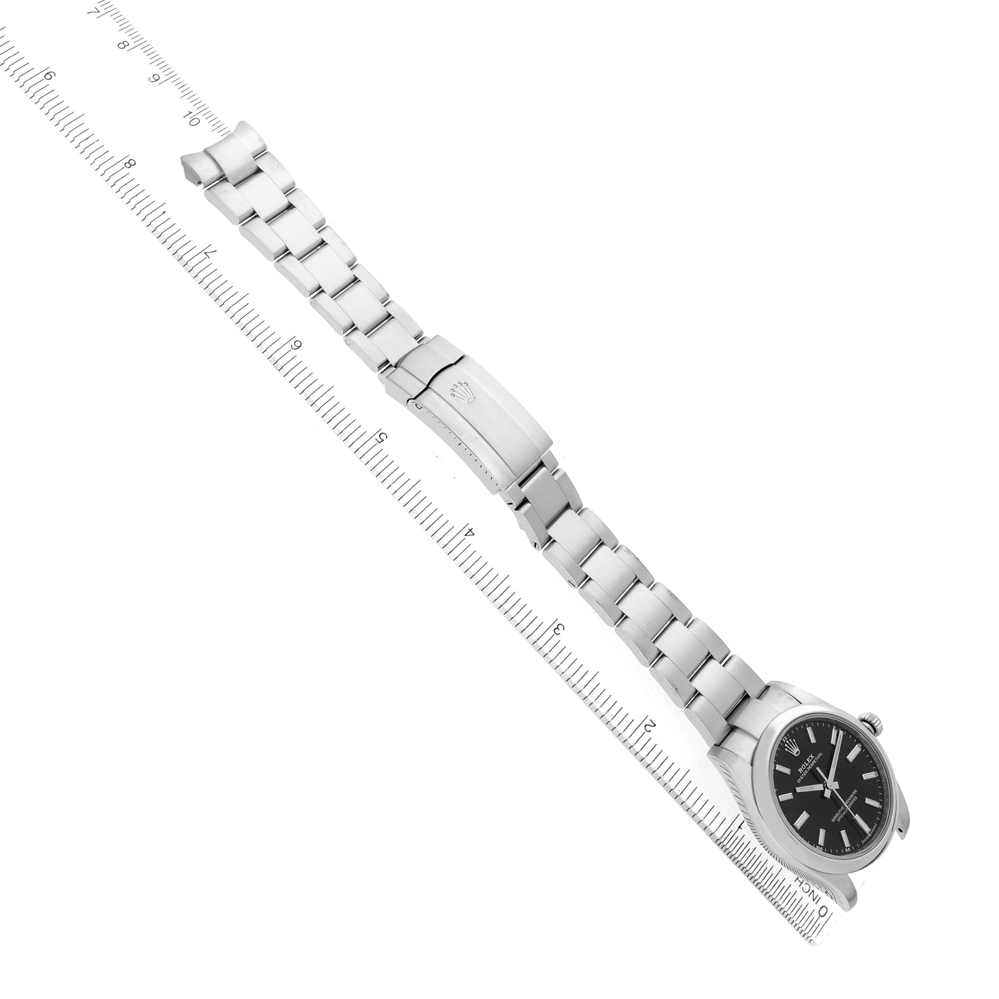 The Rolex Oyster Perpetual 124200 Men's Stainless Steel Black Dial watch is shown at an angled top view, displaying the full bracelet and face, alongside a ruler for scale.