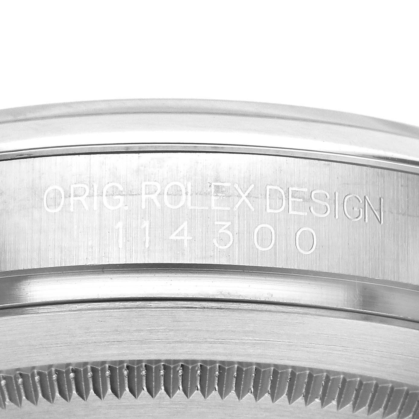 The image shows a close-up of the side engraving on the bezel of a Rolex Oyster Perpetual 114300 Men's Stainless Steel Blue Dial 114300 Men's Stainless Steel Blue Dial, focusing on the model number.