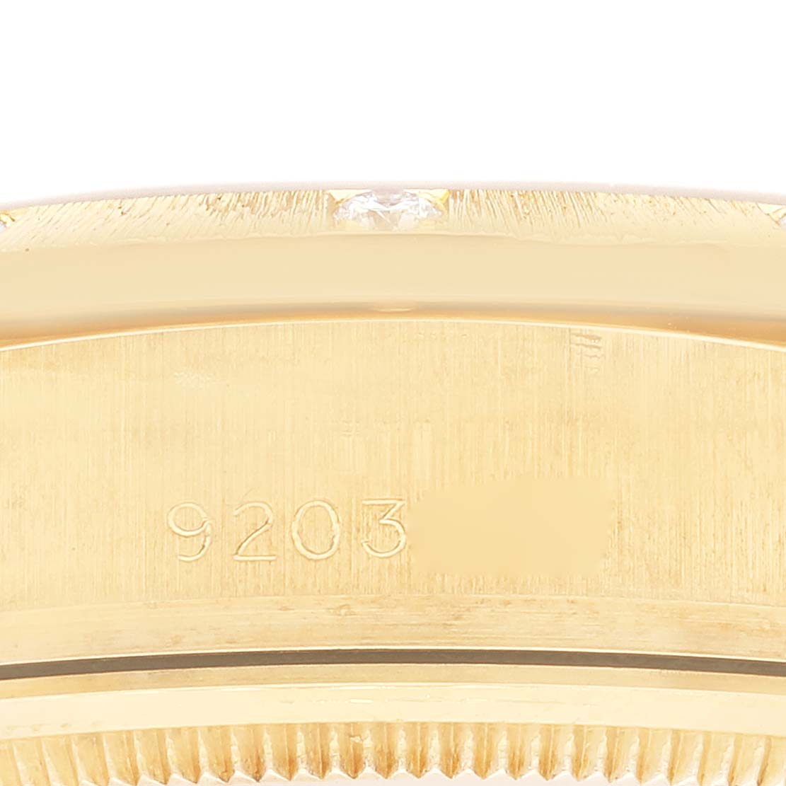 This close-up image shows part of the gold bezel and serial number of a Rolex President 18108 Men
s Yellow Gold Champagne Dial 18108 Men
s Yellow Gold Champagne Dial model watch.