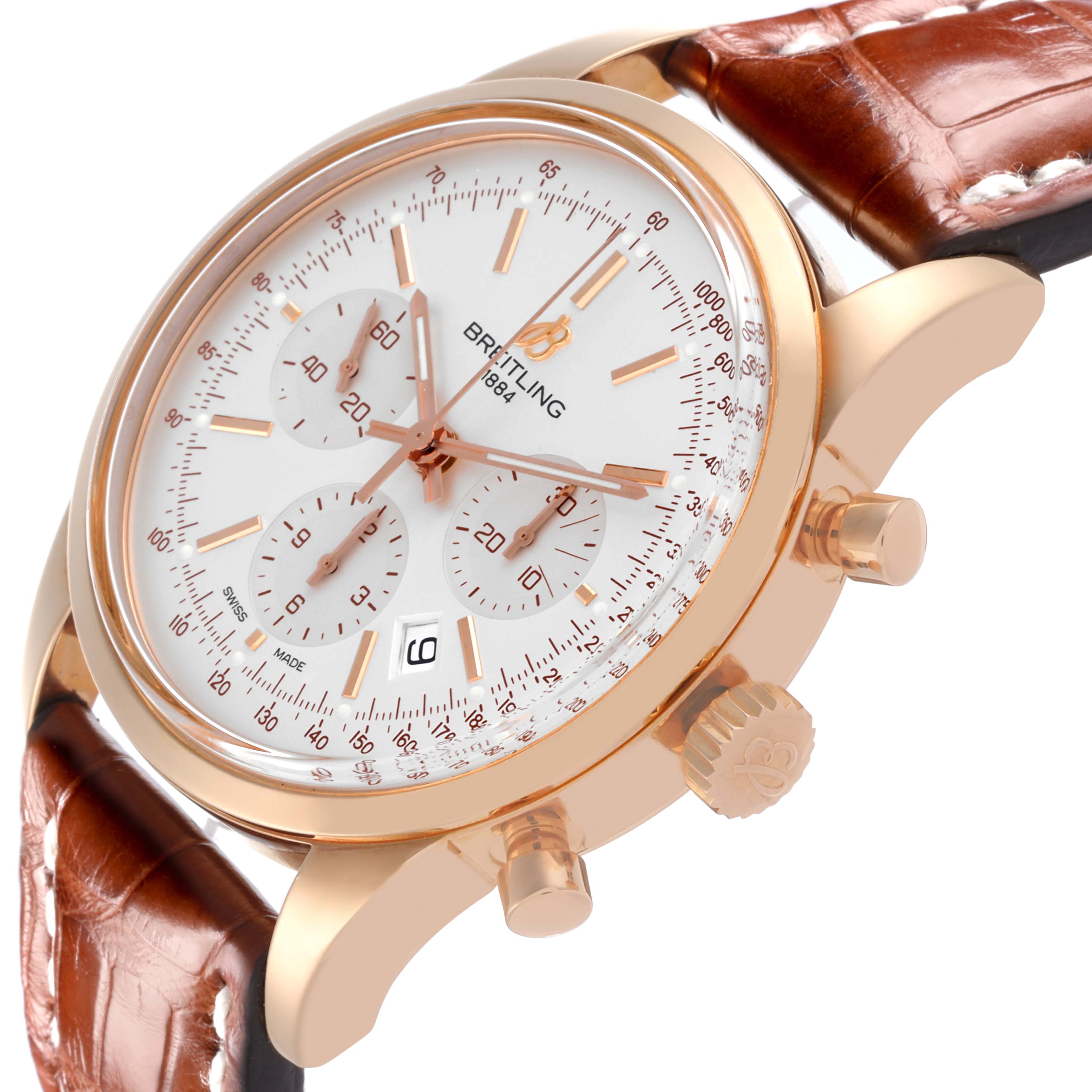 The Breitling Transocean RB0152 Men's Rose Gold Silver Dial RB0152 Men's Rose Gold Silver Dial watch is shown from a side angle, highlighting its face, bezel, chronograph dials, crown, and leather strap.