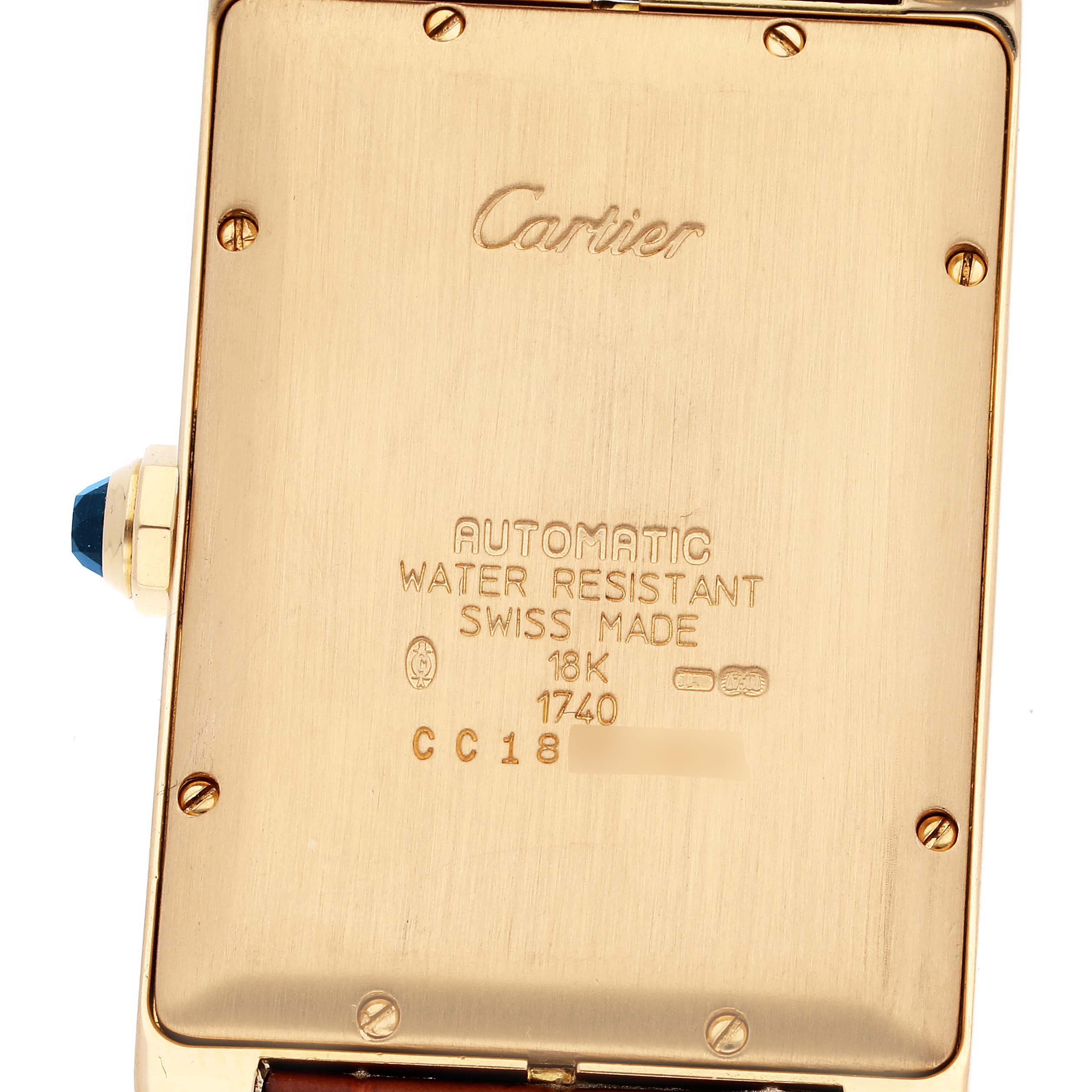This image shows the back case of the Cartier Tank Americaine W2603156 Men's Yellow Gold Silver Dial W2603156 Men's Yellow Gold Silver Dial watch, highlighting its engravings and crown.