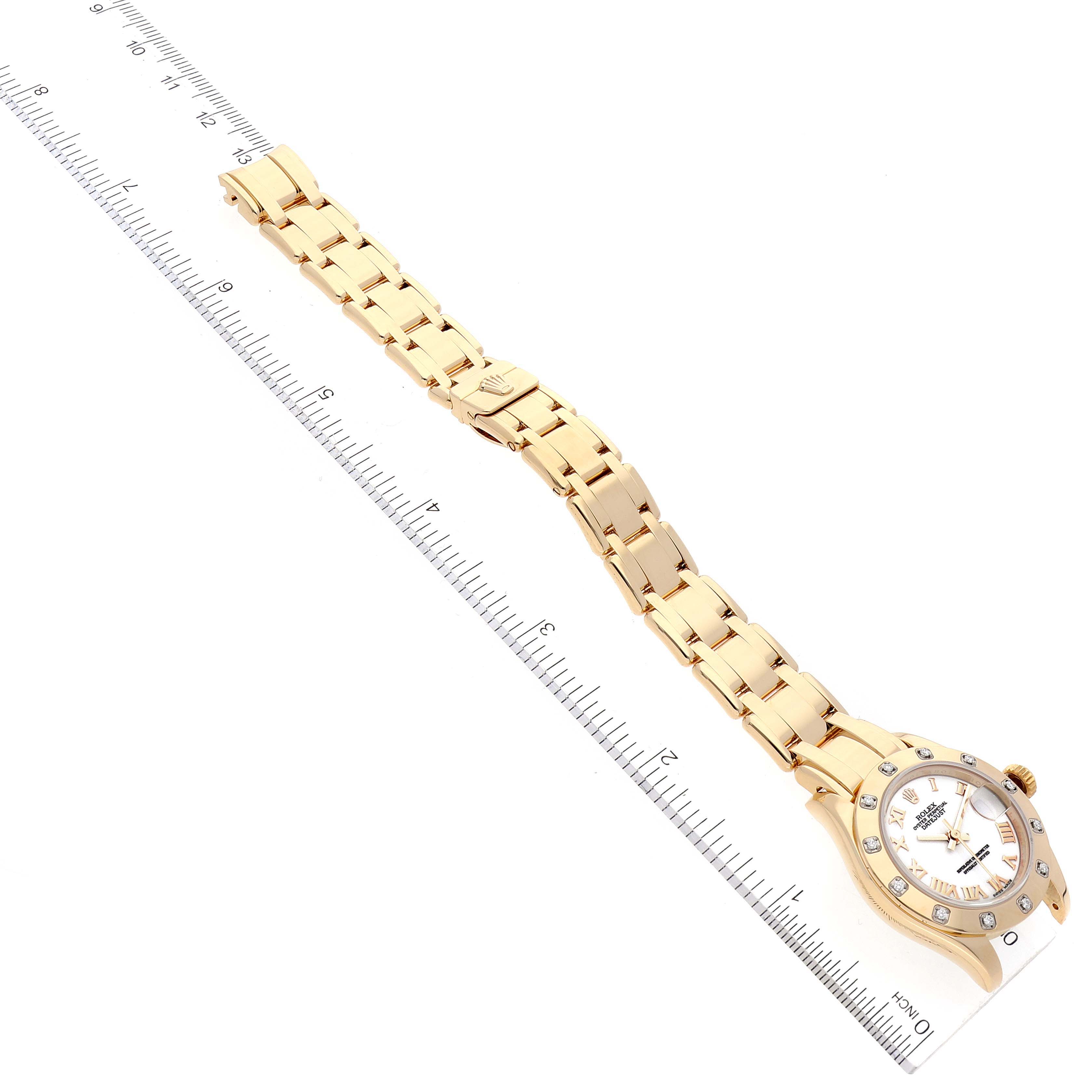 The image shows a Rolex Pearlmaster 80318 Women
s Yellow Gold White Dial 80318 Women
s Yellow Gold White Dial watch laid flat next to a ruler, highlighting the bracelet and face.