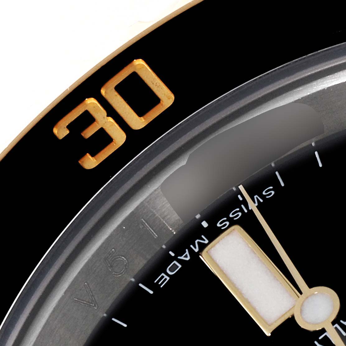 This close-up of the Rolex Submariner 116613 Men's Steel and Gold (two tone) Black Dial 116613 Men's Steel and Gold (two tone) Black Dial watch shows part of the bezel with the "30" marker and a portion of the dial with the hour hand and "Swiss Made" text.