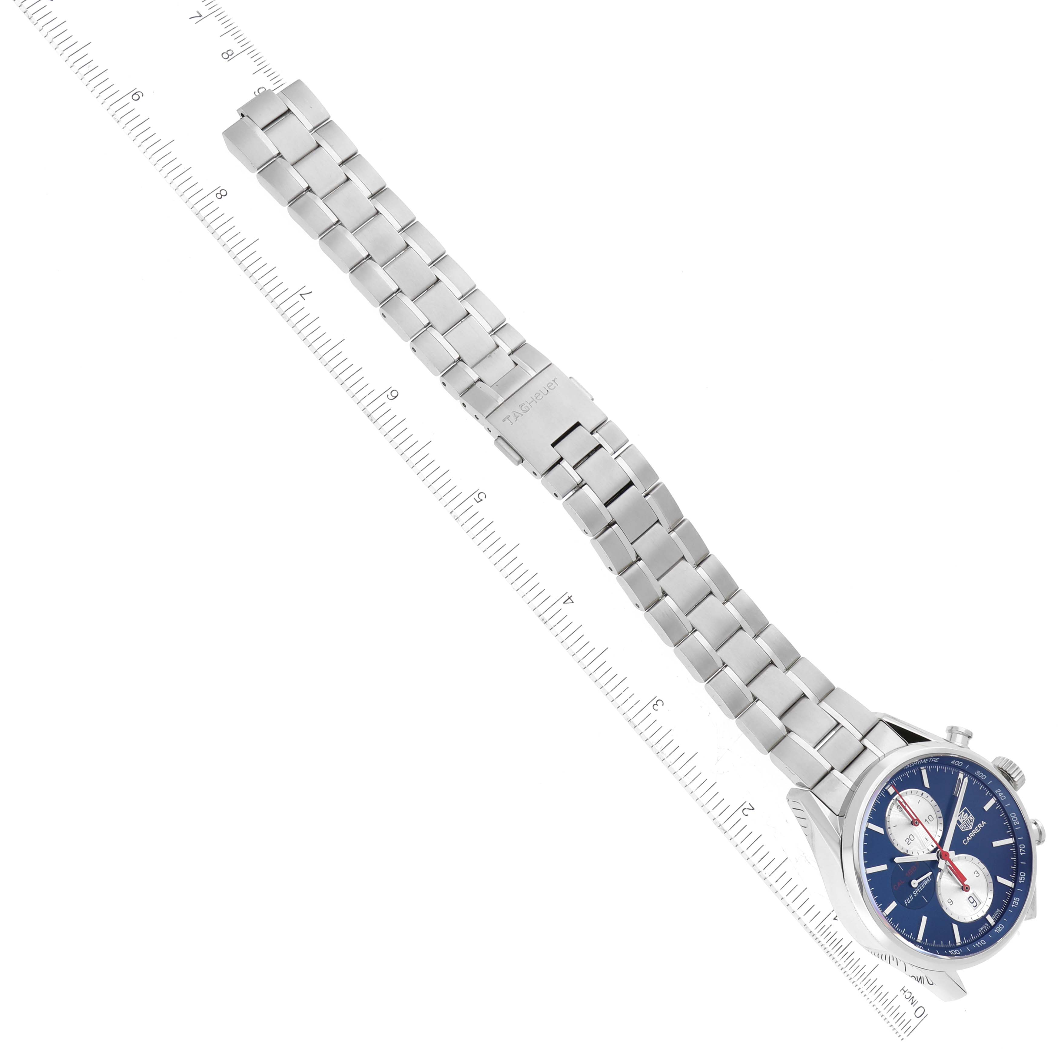 The image shows a top view of a Tag Heuer Limited Edition CAR211B Men's Stainless Steel Blue Dial CAR211B Men's Stainless Steel Blue Dial watch with a blue dial and a silver metal bracelet, placed next to a ruler.