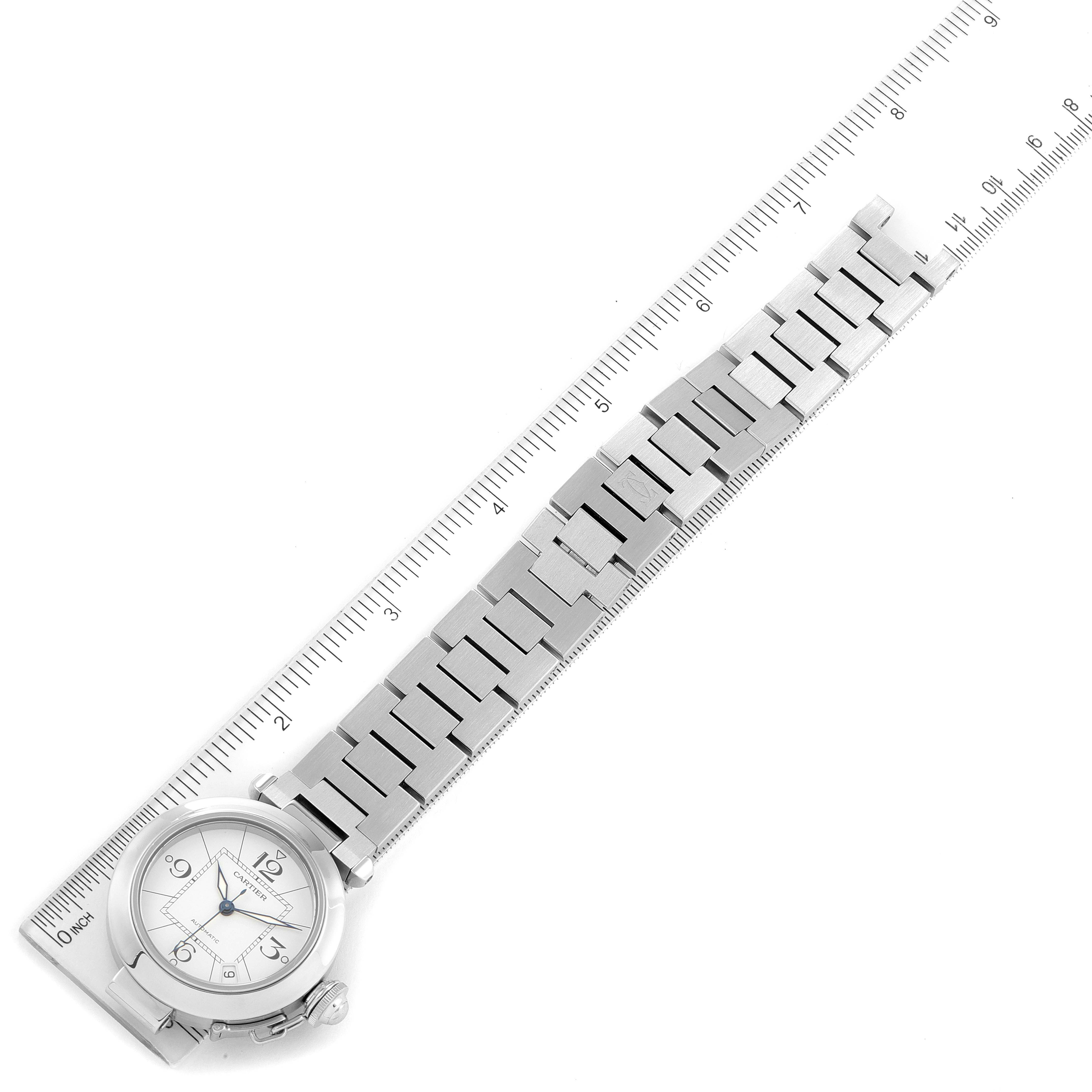 The Cartier Pasha W31074M7 Women's Stainless Steel White Dial W31074M7 Women's Stainless Steel White Dial watch is shown from a top-down angle, displaying the dial, case, and stainless steel bracelet along a ruler for scale.