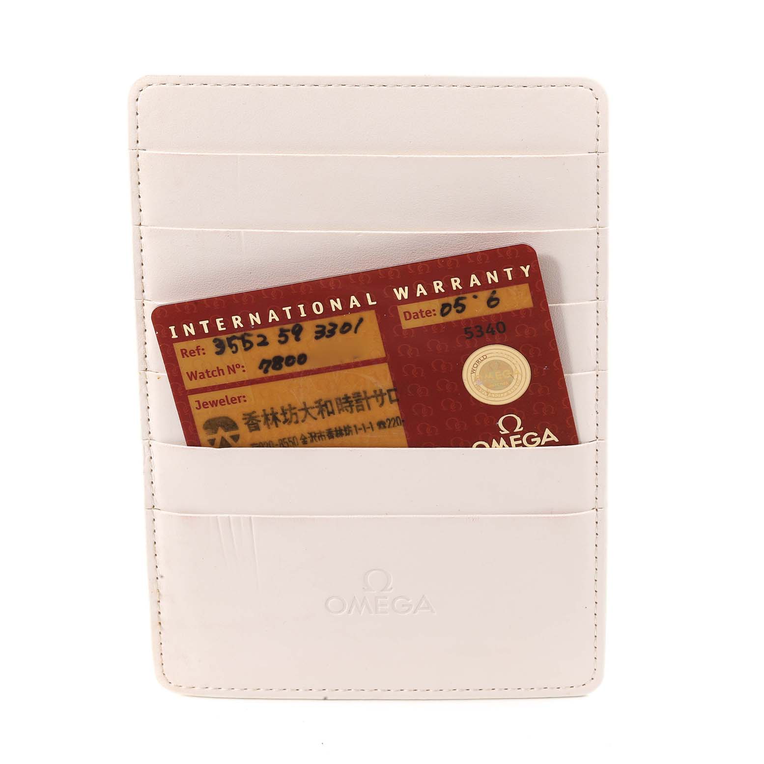 The image shows a white Omega Speedmaster 3552.59.00 Men
s Stainless Steel Black Dial 3552.59.00 Men
s Stainless Steel Black Dial international warranty cardholder with a red warranty card partially visible.