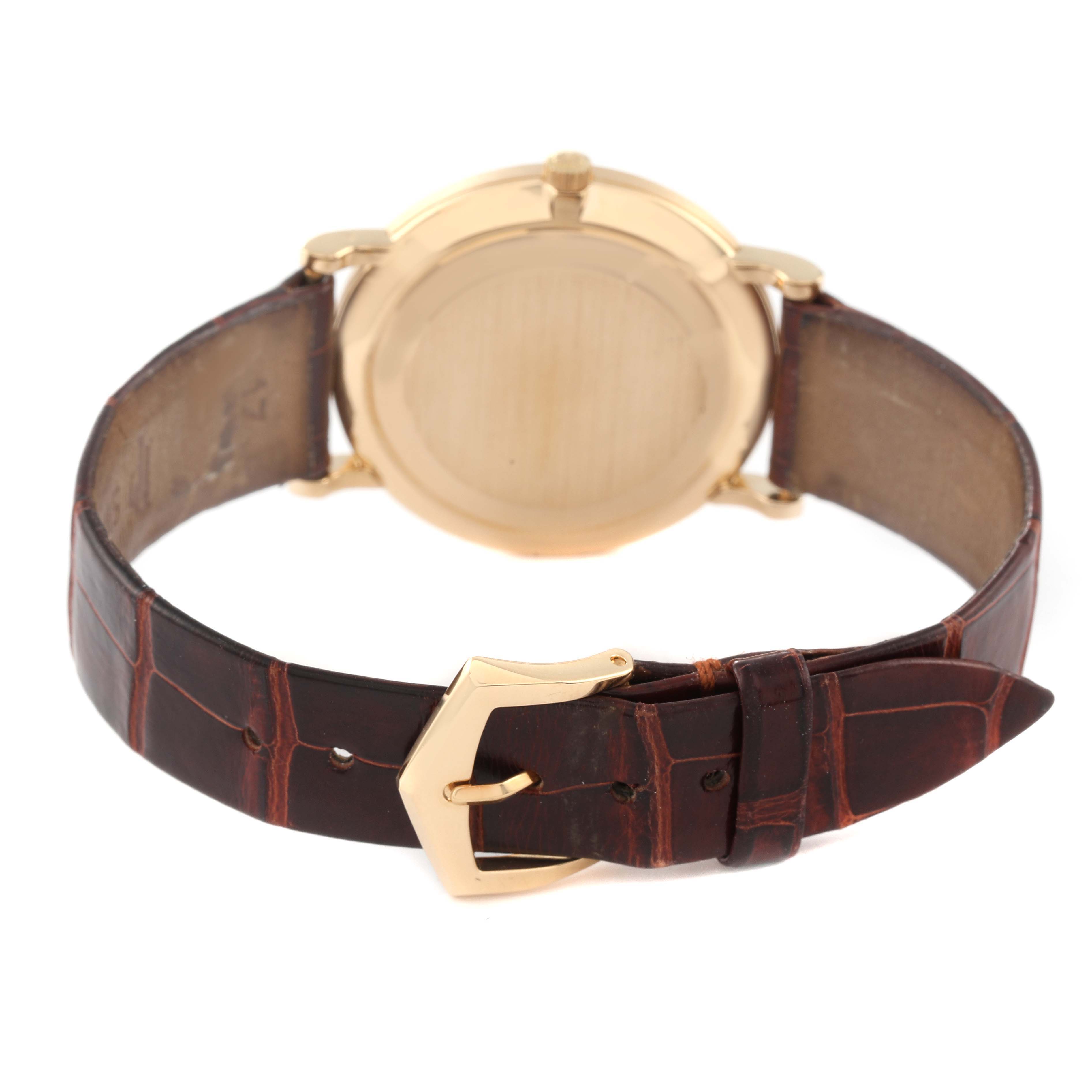 The image shows the back view of a Patek Philippe Calatrava 3919J Men's Yellow Gold White Dial 3919J Men's Yellow Gold White Dial watch featuring its case and leather strap with a buckle.