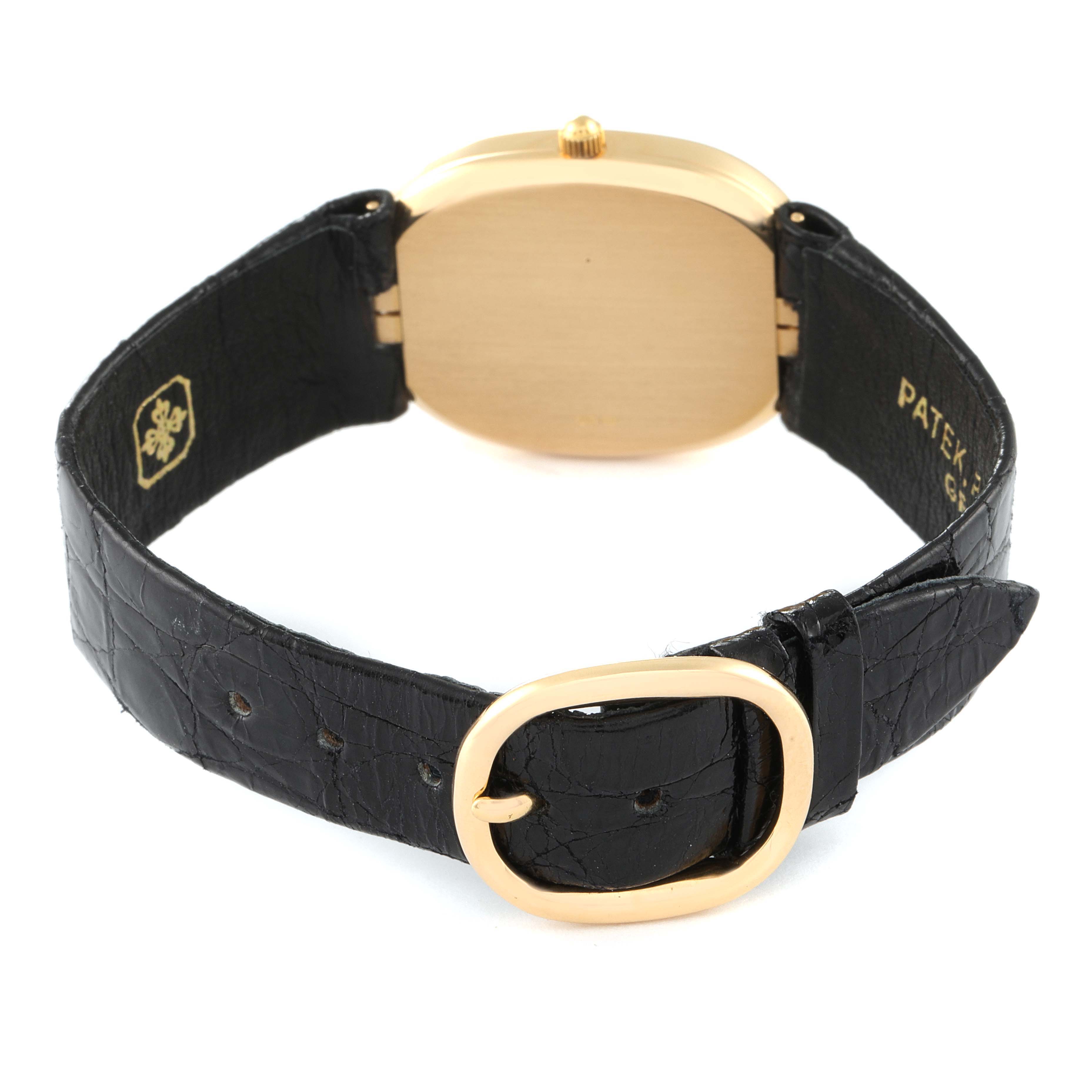The image shows the back view of a Patek Philippe Golden Ellipse 3788 Men's Yellow Gold Beige Dial 3788 Men's Yellow Gold Beige Dial watch with a black leather strap and gold buckle.