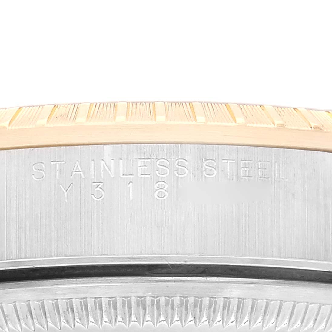 The image shows a close-up of the side of a Rolex Date 15223 Men
s Steel and Gold (two tone) Blue Dial 15223 Men
s Steel and Gold (two tone) Blue Dial watch, focusing on the stainless steel engraving and part of the bezel.