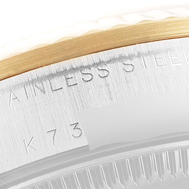 This close-up image of a Rolex Mid-Size 78273 Women's Steel and Gold (two tone) Champagne Dial 78273 Women's Steel and Gold (two tone) Champagne Dial model watch shows the edge of the bezel and part of the case back, including some engraving.
