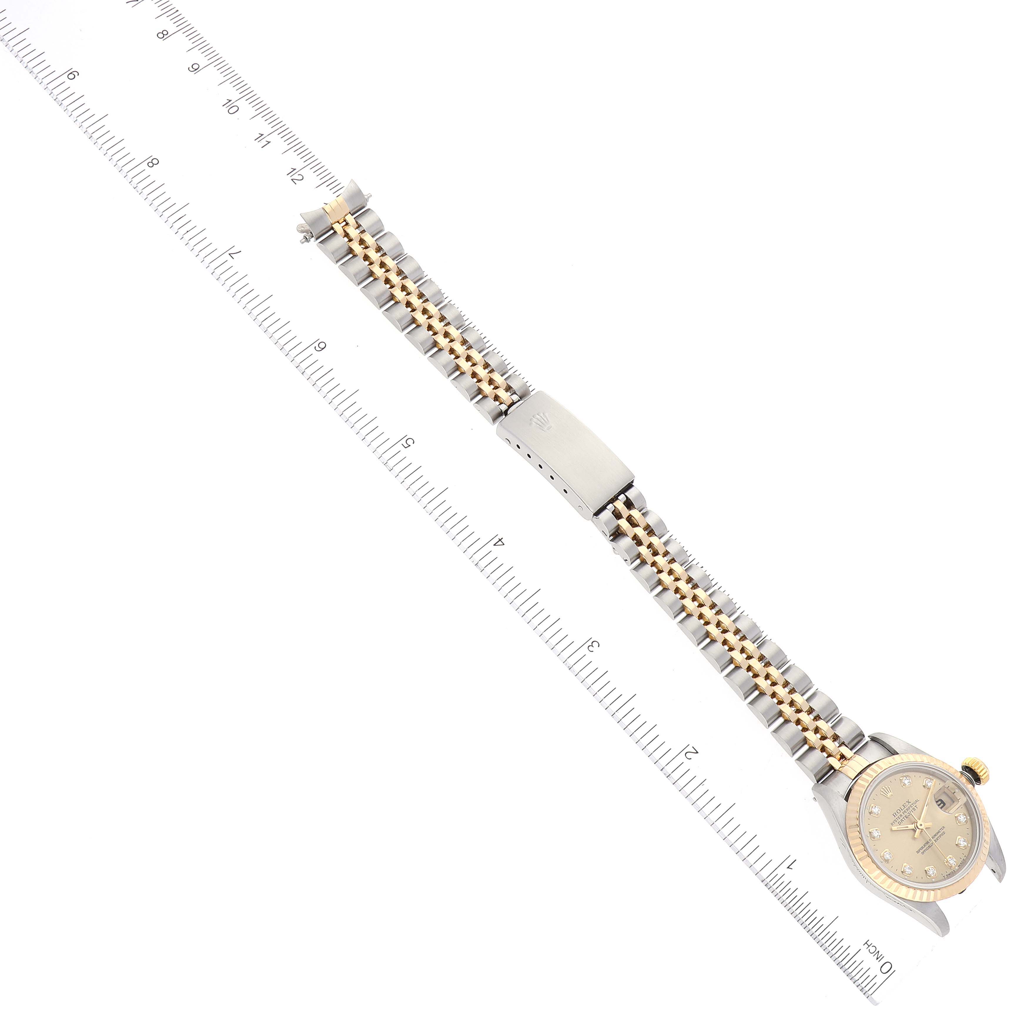 The Rolex Datejust 69173 Women's Steel and Gold (two tone) Champagne Dial 69173 Women's Steel and Gold (two tone) Champagne Dial watch is shown from a top-down angle, displaying the face, band, and clasp with a ruler for scale.