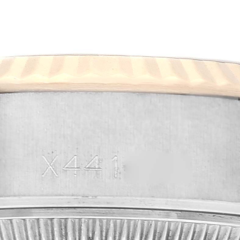 The image shows a close-up of the side of a Rolex Datejust 69173 Women's Steel and Gold (two tone) Champagne Dial 69173 Women's Steel and Gold (two tone) Champagne Dial watch, featuring part of its fluted bezel and case with an engraved serial number.