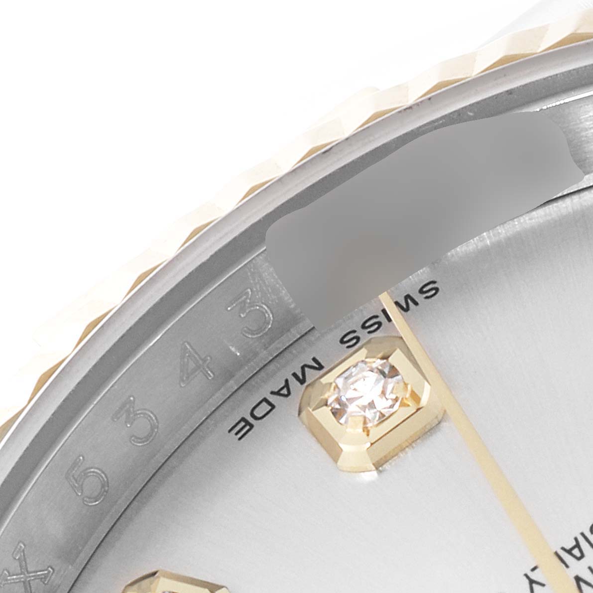This image shows the edge of the dial and bezel of the Rolex Datejust 116233 Men's Steel and Gold (two tone) Silver Dial 116233 Men's Steel and Gold (two tone) Silver Dial watch, highlighting a diamond marker and part of the "Swiss Made" text.