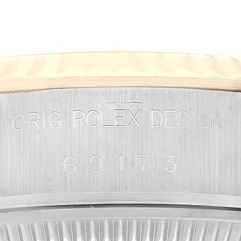 This image shows a close-up of the case side of a Rolex Datejust 69173 Women's Steel and Gold (two tone) Grey Dial 69173 Women's Steel and Gold (two tone) Grey Dial, featuring engraving and part of the fluted bezel.