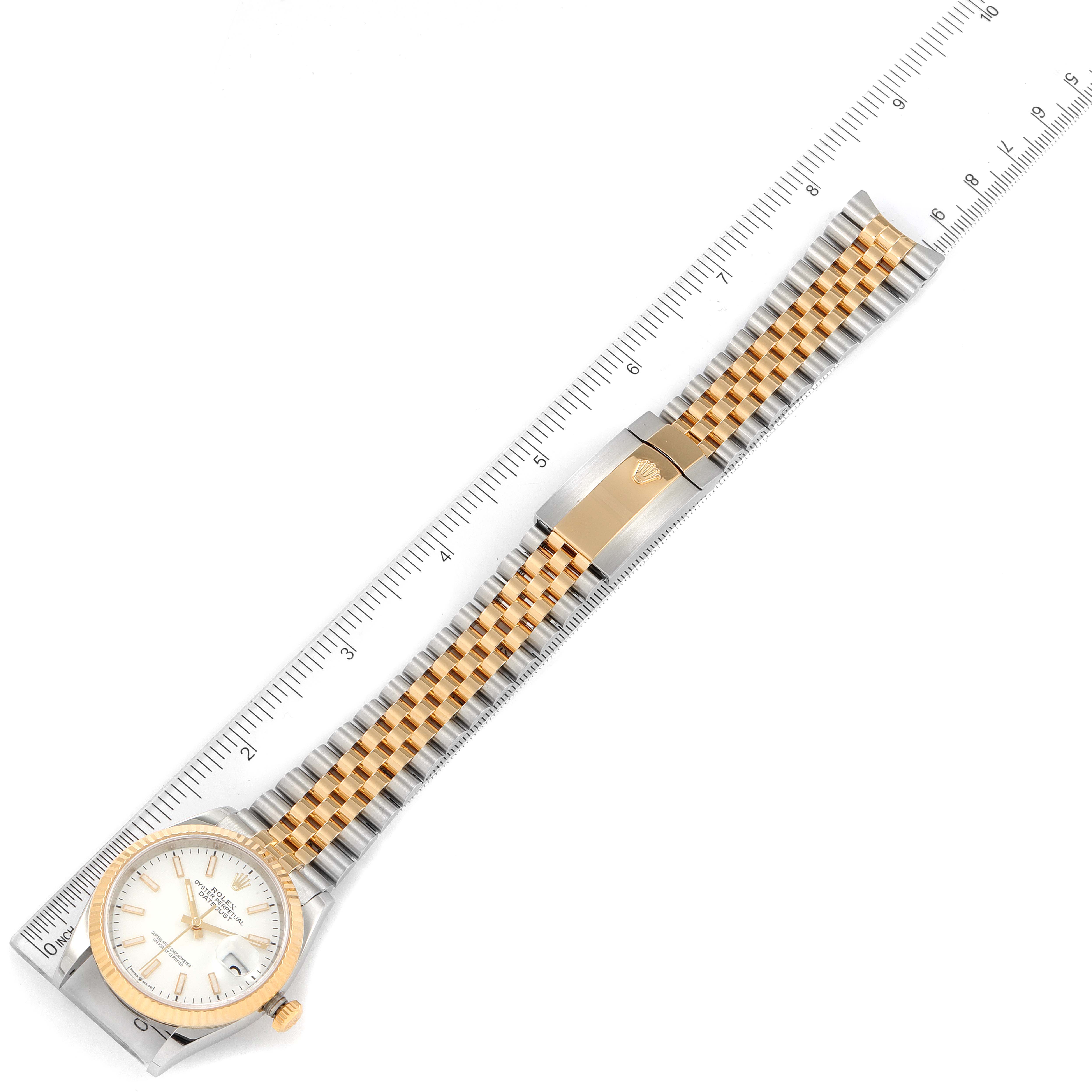 The image shows a Rolex Datejust 126233 Men's Steel and Gold (two tone) White Dial 126233 Men's Steel and Gold (two tone) White Dial watch laid flat on a ruler, displaying the face, bezel, and bracelet with clasp.
