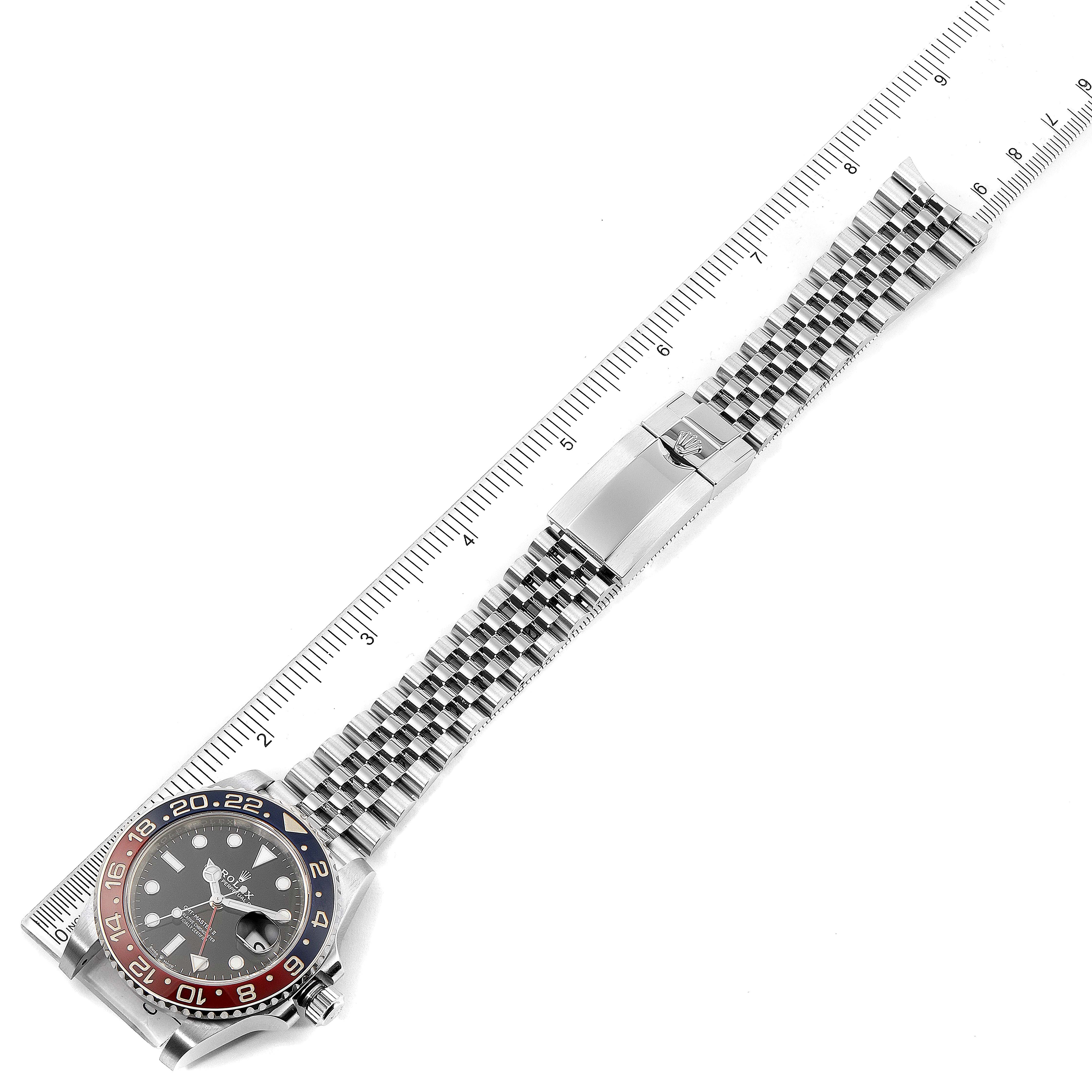 The image shows a Rolex GMT-Master 126710 Men
s Stainless Steel Black Dial 126710 Men
s Stainless Steel Black Dial watch lying flat with its face and bracelet extended next to a ruler for scale.