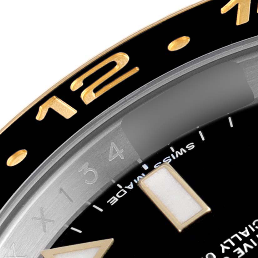 This close-up of the Rolex GMT-Master 116713 Men's Steel and Gold (two tone) Black Dial 116713 Men's Steel and Gold (two tone) Black Dial watch displays part of the black and gold bezel, hour markers, and the "Swiss Made" text.