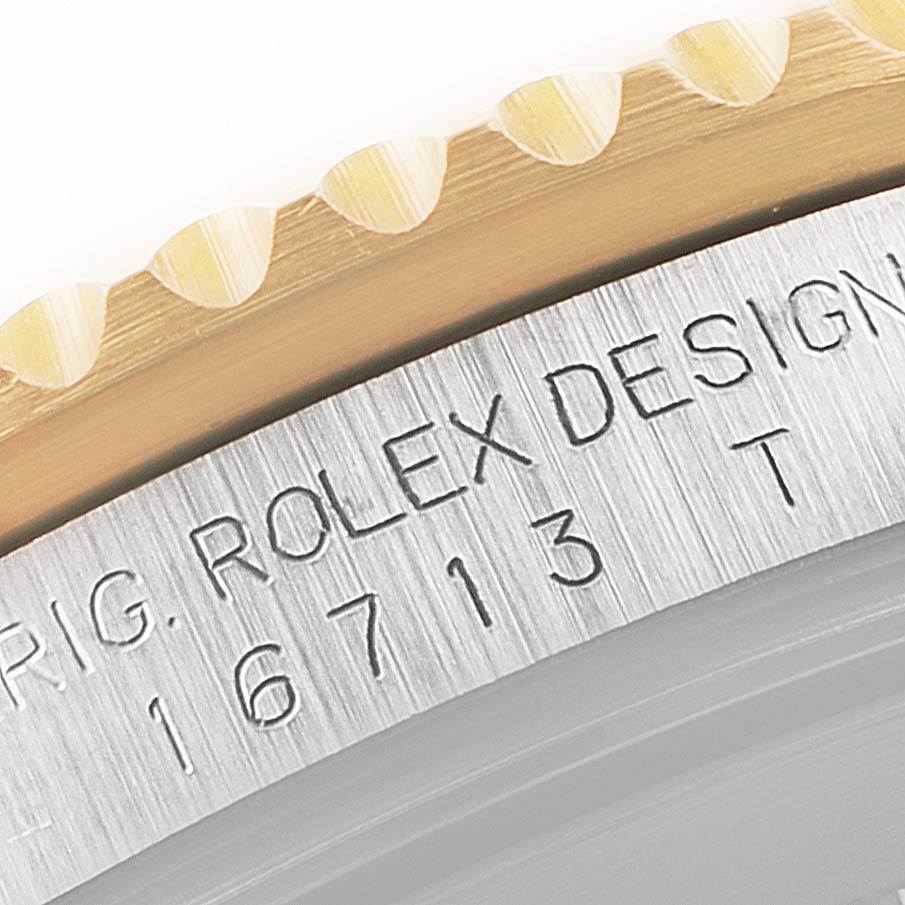 This close-up image shows the edge of the bezel and part of the caseback engraving on a Rolex GMT-Master 16713 Men's Steel and Gold (two tone) Black Dial 16713 Men's Steel and Gold (two tone) Black Dial watch.