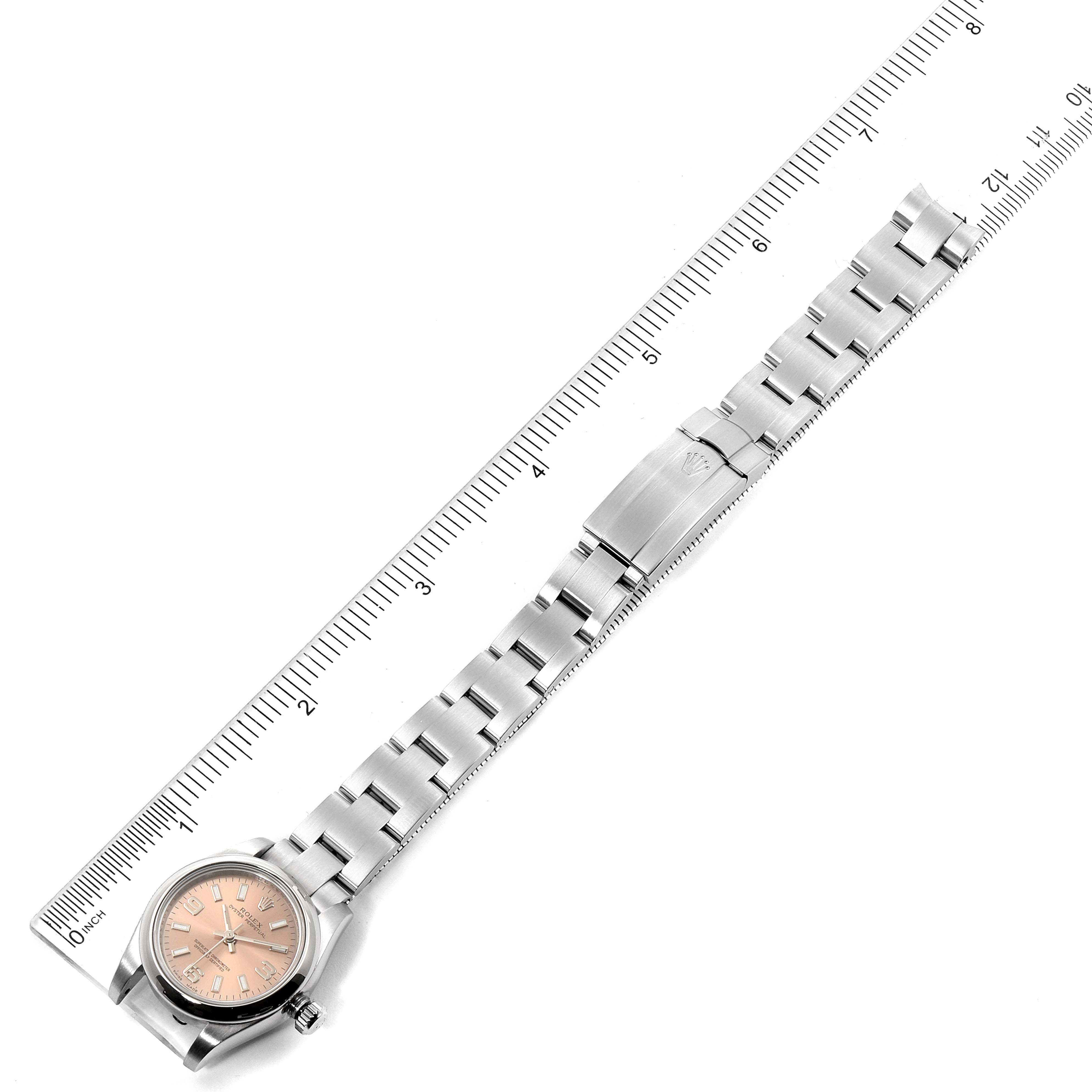 This image shows a Rolex Oyster Perpetual 176200 Women's Stainless Steel Pink Dial 176200 Women's Stainless Steel Pink Dial watch laid flat with its bracelet extended alongside a ruler.