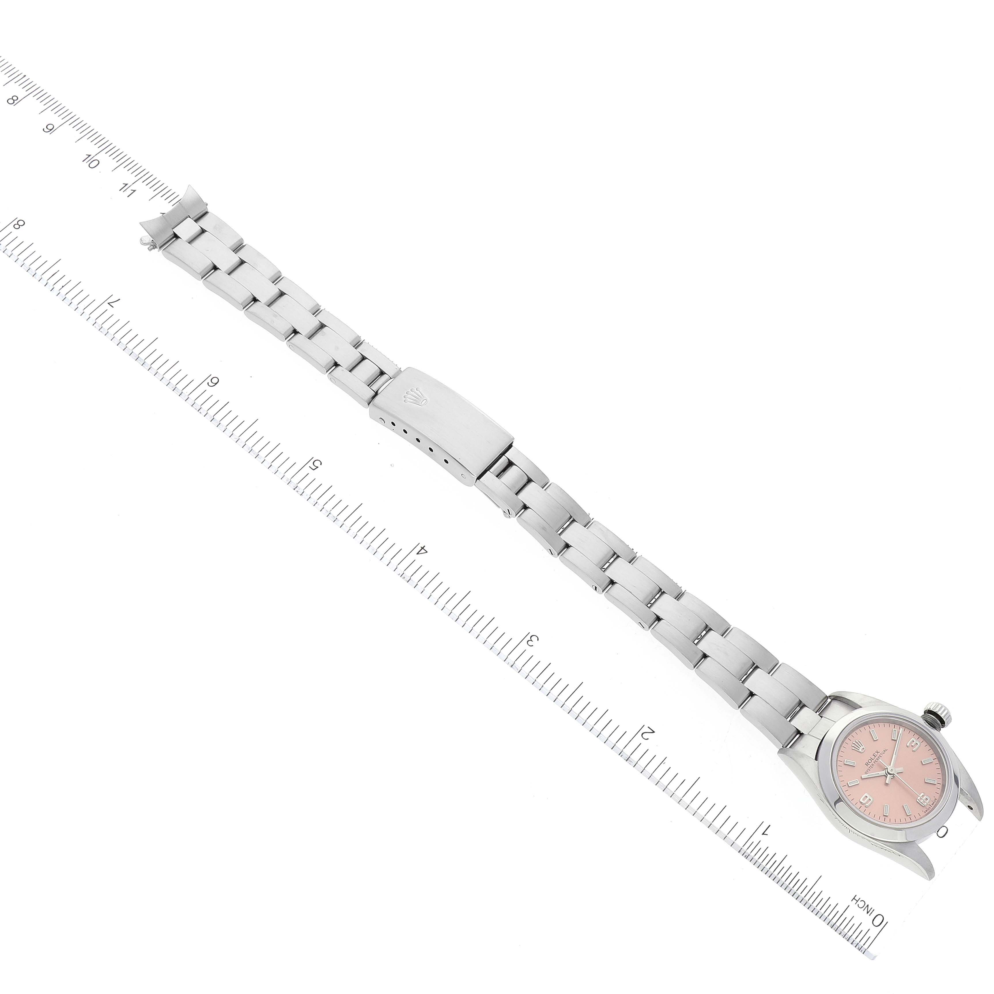 This image shows a Rolex Datejust 76080 Women's Stainless Steel Pink Dial 76080 Women's Stainless Steel Pink Dial watch with a pink dial and full metal bracelet laid flat next to a ruler.