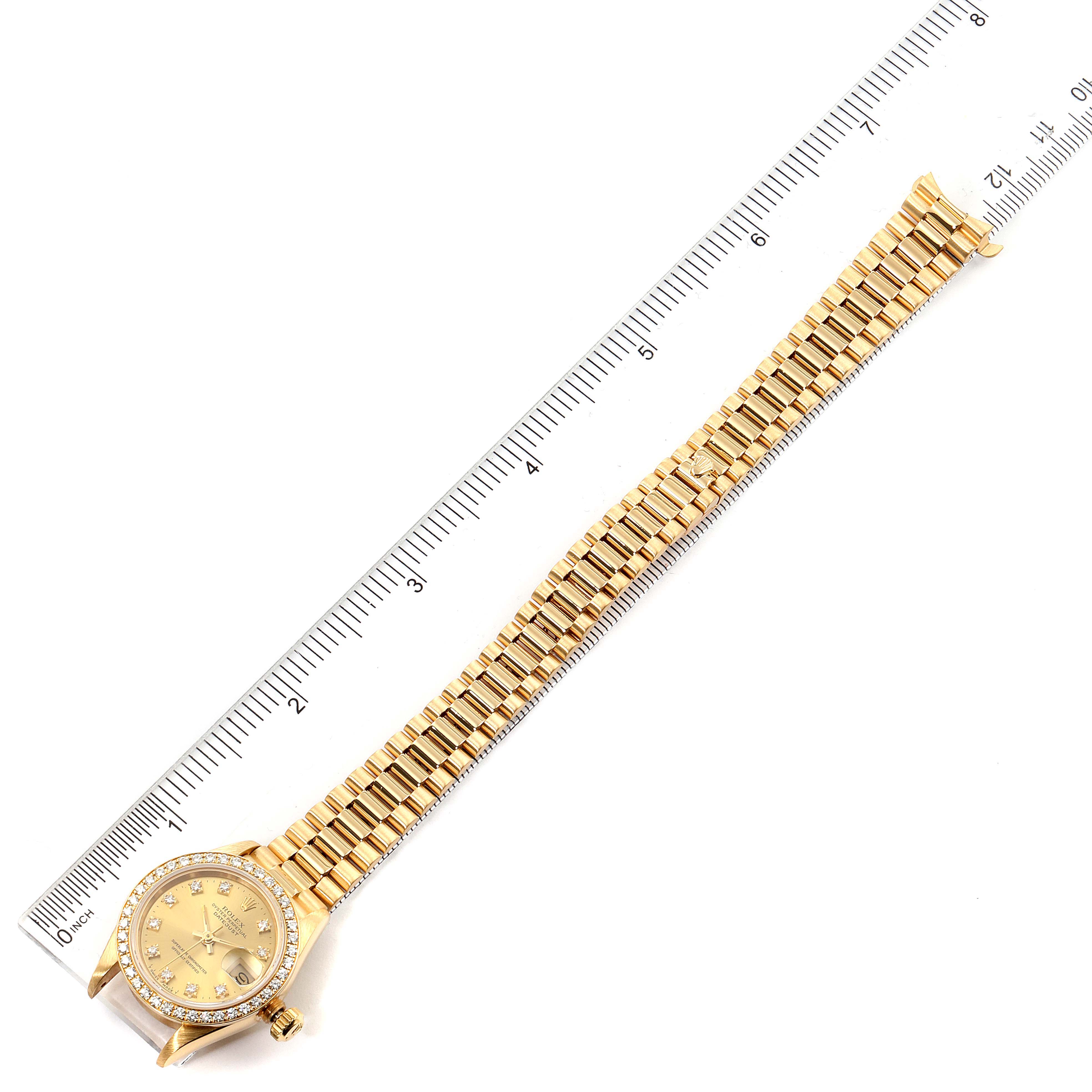 The image shows a gold Rolex President 69138 Women
s Yellow Gold Champagne Dial 69138 Women
s Yellow Gold Champagne Dial model watch, laid flat alongside a ruler for scale, displaying the full watch and bracelet.