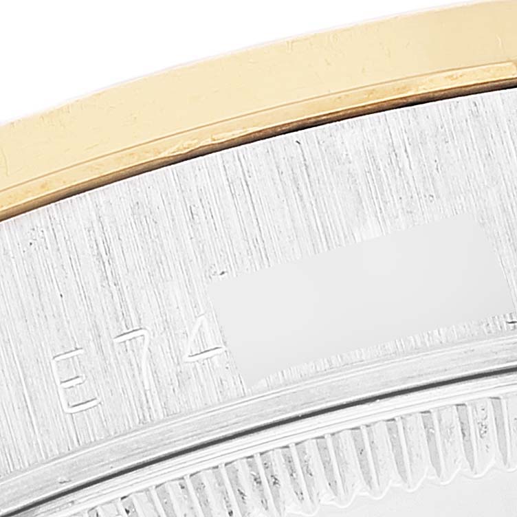This close-up image of a Mid-Size Rolex watch shows part of the bezel and the engraved serial number on the case.