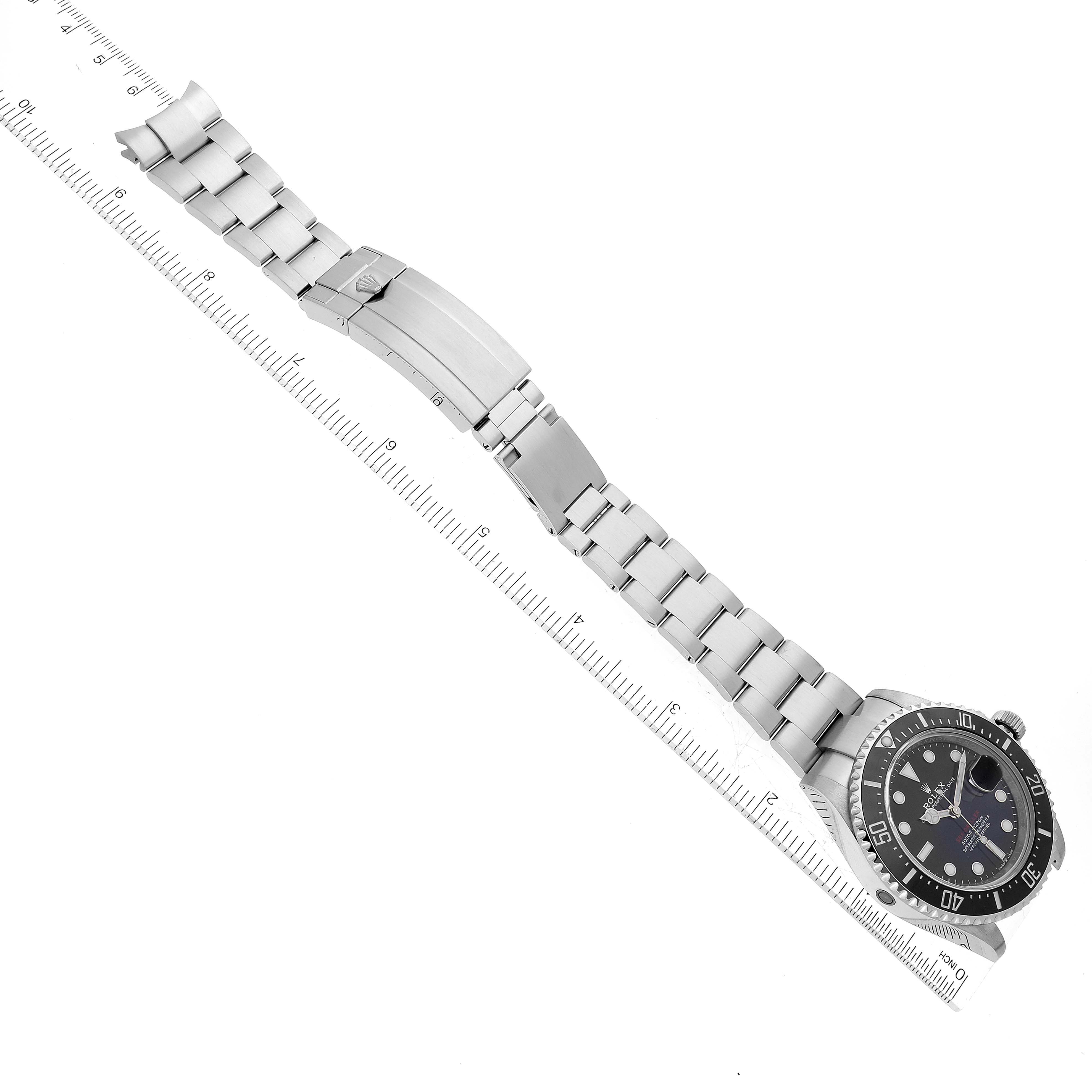 The Rolex Sea-Dweller 126600 Men
s Stainless Steel Black Dial 126600 Men
s Stainless Steel Black Dial watch is displayed flat, showcasing the face, bracelet, and clasp from a top-down angle with a ruler for scale.