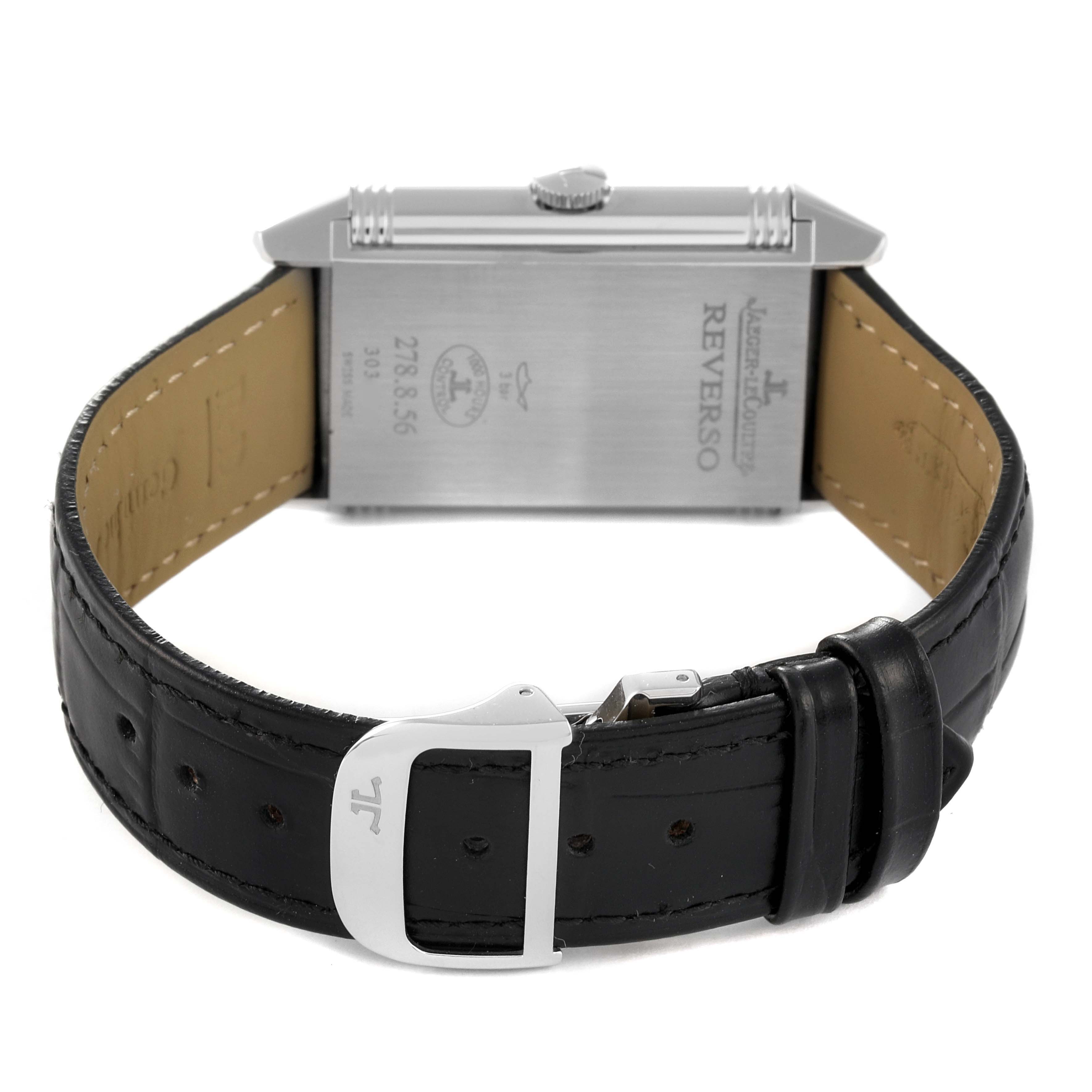 The image shows the back of a Jaeger-LeCoultre Reverso watch and its black leather strap with a deployant clasp.
