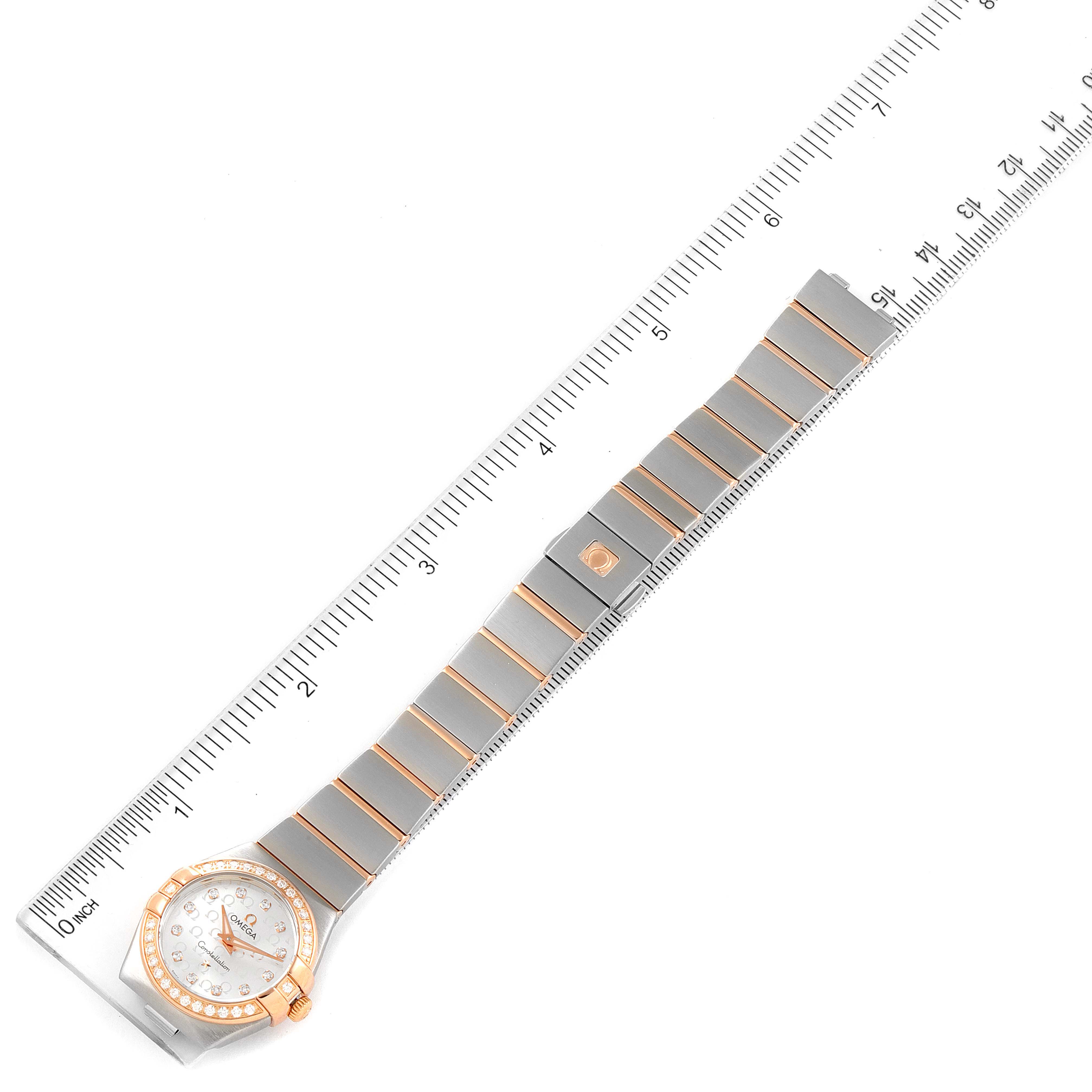 The Omega 123.25.24.60.55.009 Women's Steel and Gold (two tone) Silver Dial 123.25.24.60.55.009 Women's Steel and Gold (two tone) Silver Dial Constellation Steel Yellow Gold Diamond Ladies Watch 123.25.24.60.55.009 is displayed flat against a marked ruler.