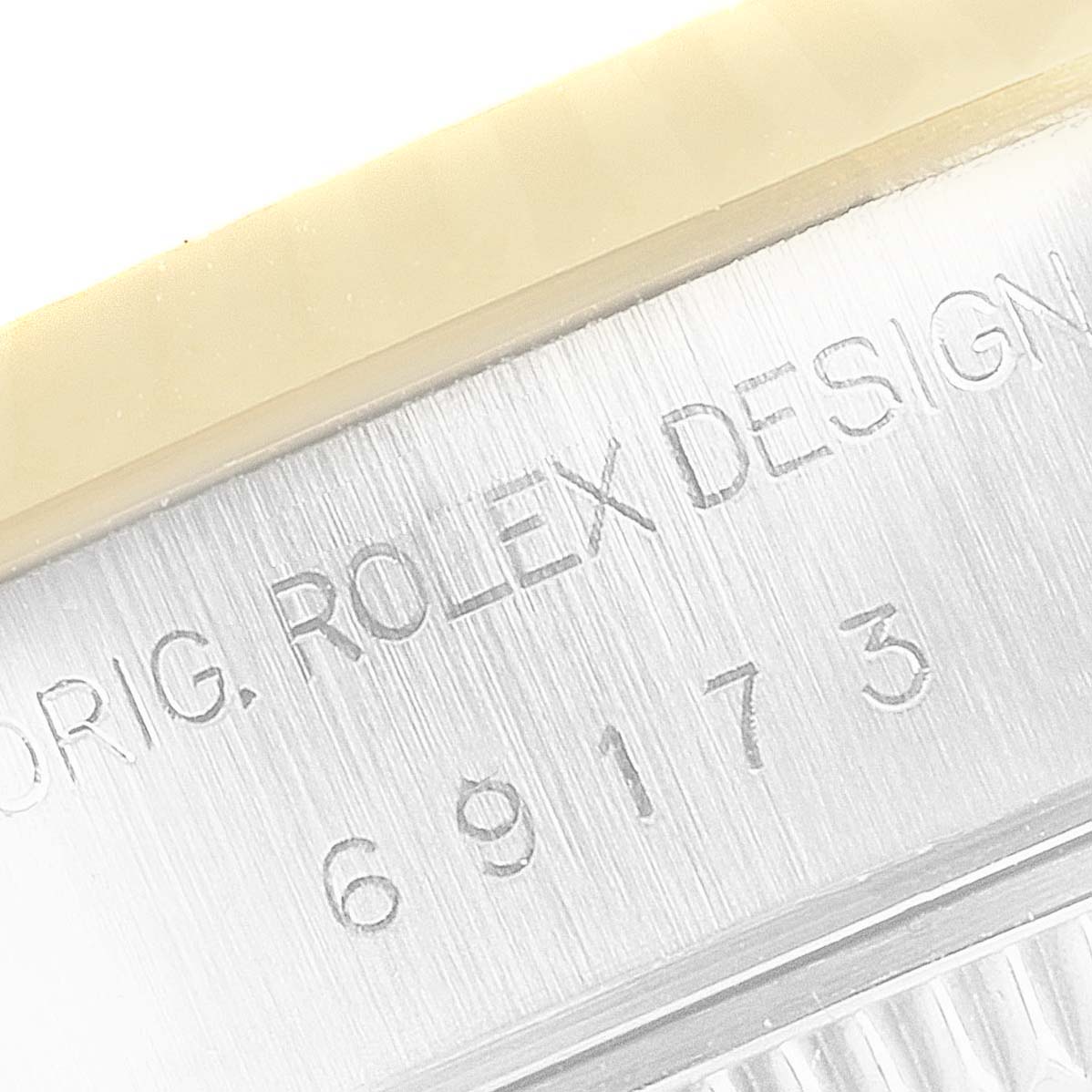 This close-up image shows the case side of a Rolex Datejust 69173 Women
s Steel and Gold (two tone) Champagne Dial 69173 Women
s Steel and Gold (two tone) Champagne Dial watch, featuring the engraved "ROLEX DESIGN" text and model number.