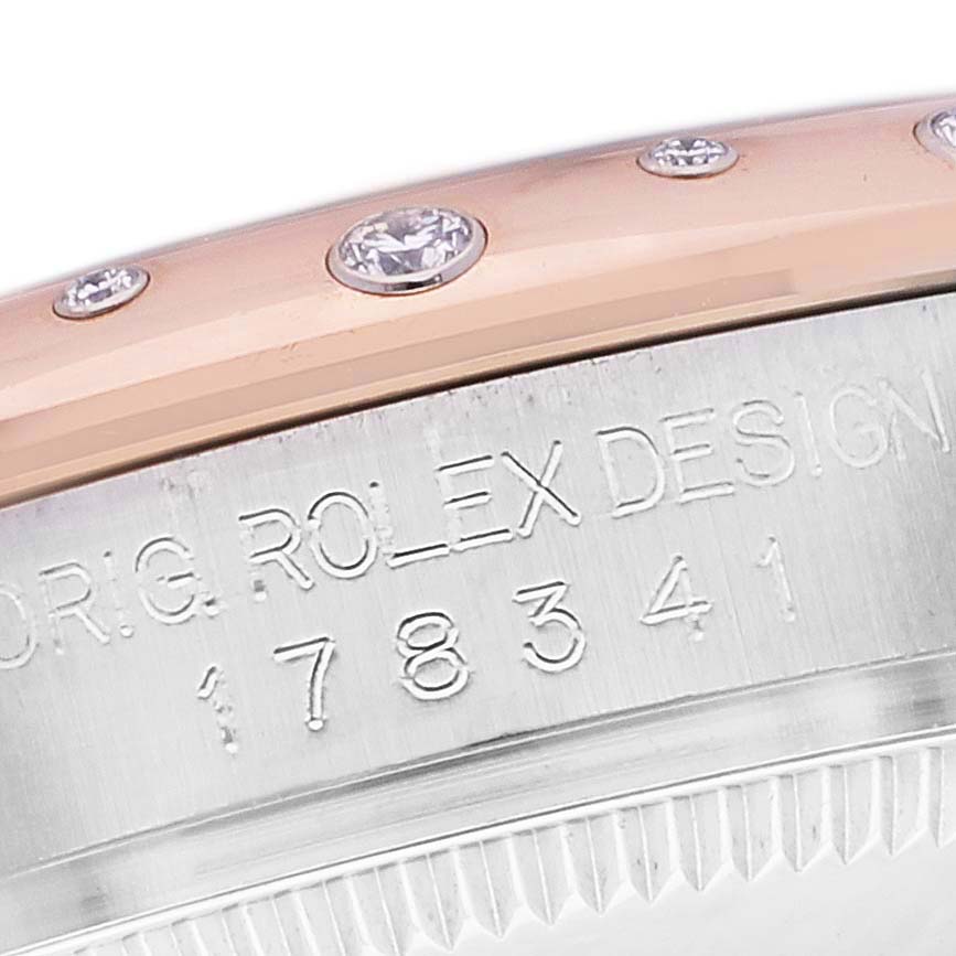 This close-up image of the Rolex Mid-Size 178341 Women's Steel and Gold (two tone) Brown Dial 178341 Women's Steel and Gold (two tone) Brown Dial model watch shows the bezel with diamond accents and engraved design numbers.