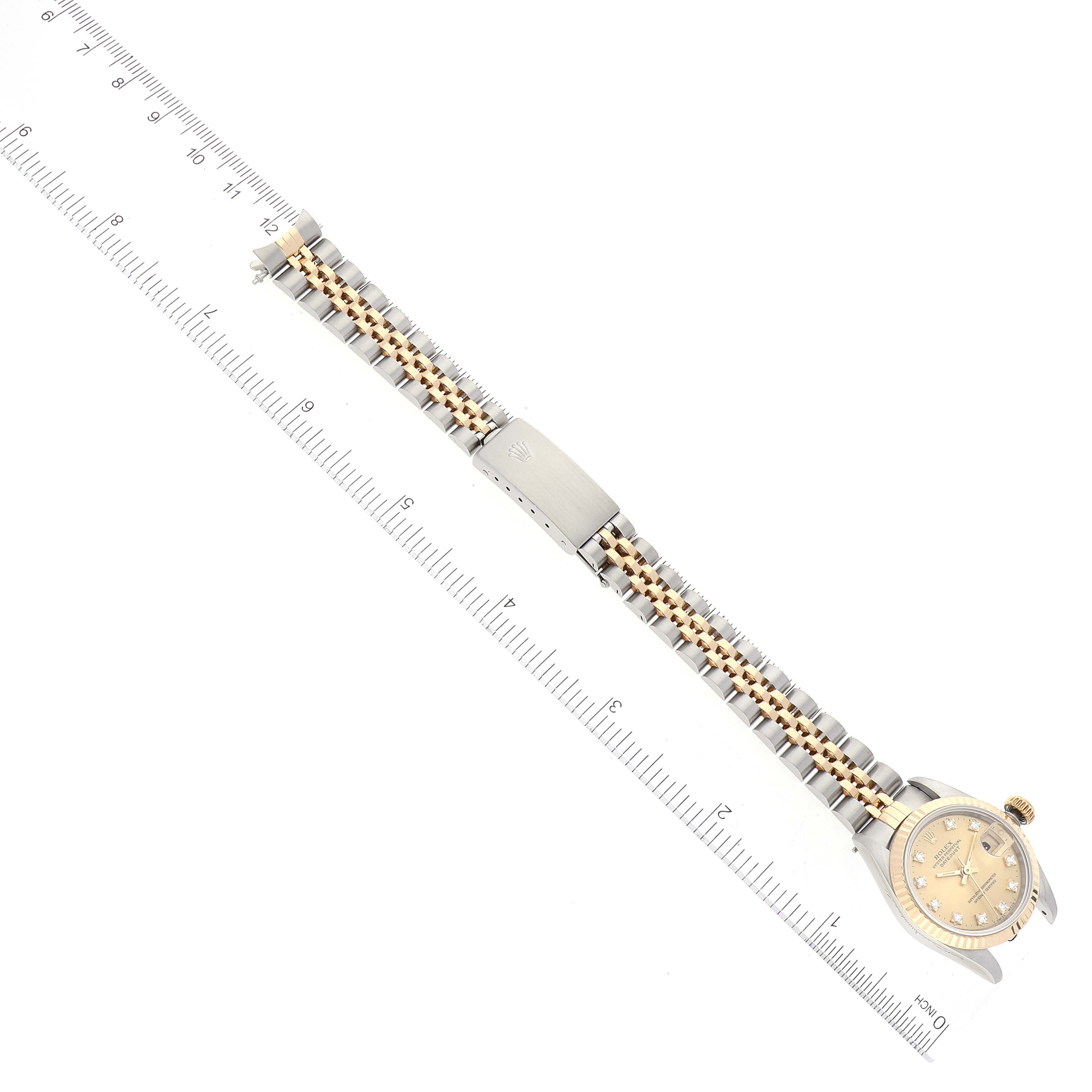 This image shows a Rolex Datejust 69173 Women's Steel and Gold (two tone) Champagne Dial 69173 Women's Steel and Gold (two tone) Champagne Dial watch laid flat against a ruler, displaying the watch face, clasp, and bracelet.