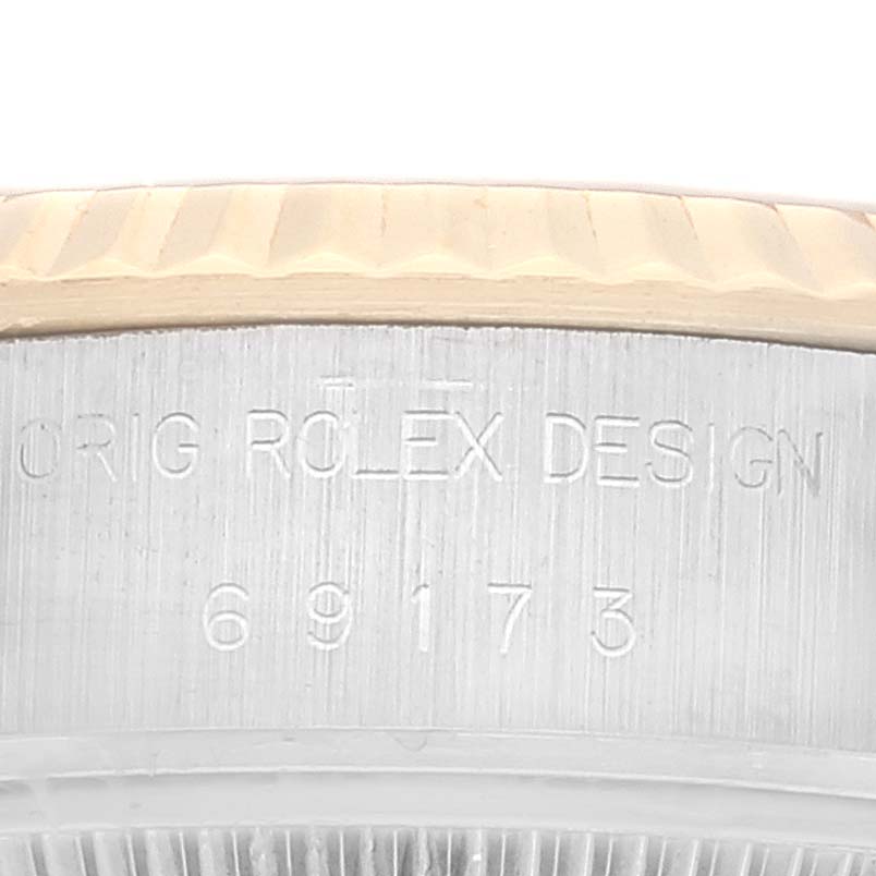 This close-up image shows the side of a Rolex Datejust 69173 Women's Steel and Gold (two tone) Champagne Dial 69173 Women's Steel and Gold (two tone) Champagne Dial watch, including the bezel and part of the case with engraved text.