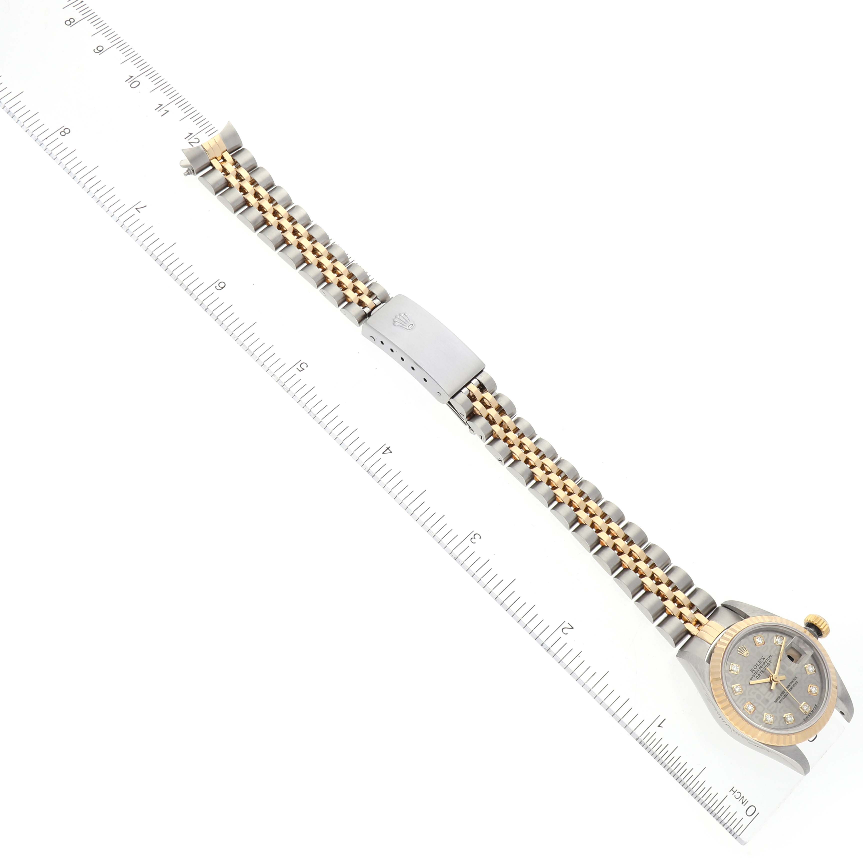 The image shows a Rolex Datejust 79173 Women's Steel and Gold (two tone) Grey Dial 79173 Women's Steel and Gold (two tone) Grey Dial watch laid flat, with a clear view of its band, clasp, and face, alongside a ruler for scale.