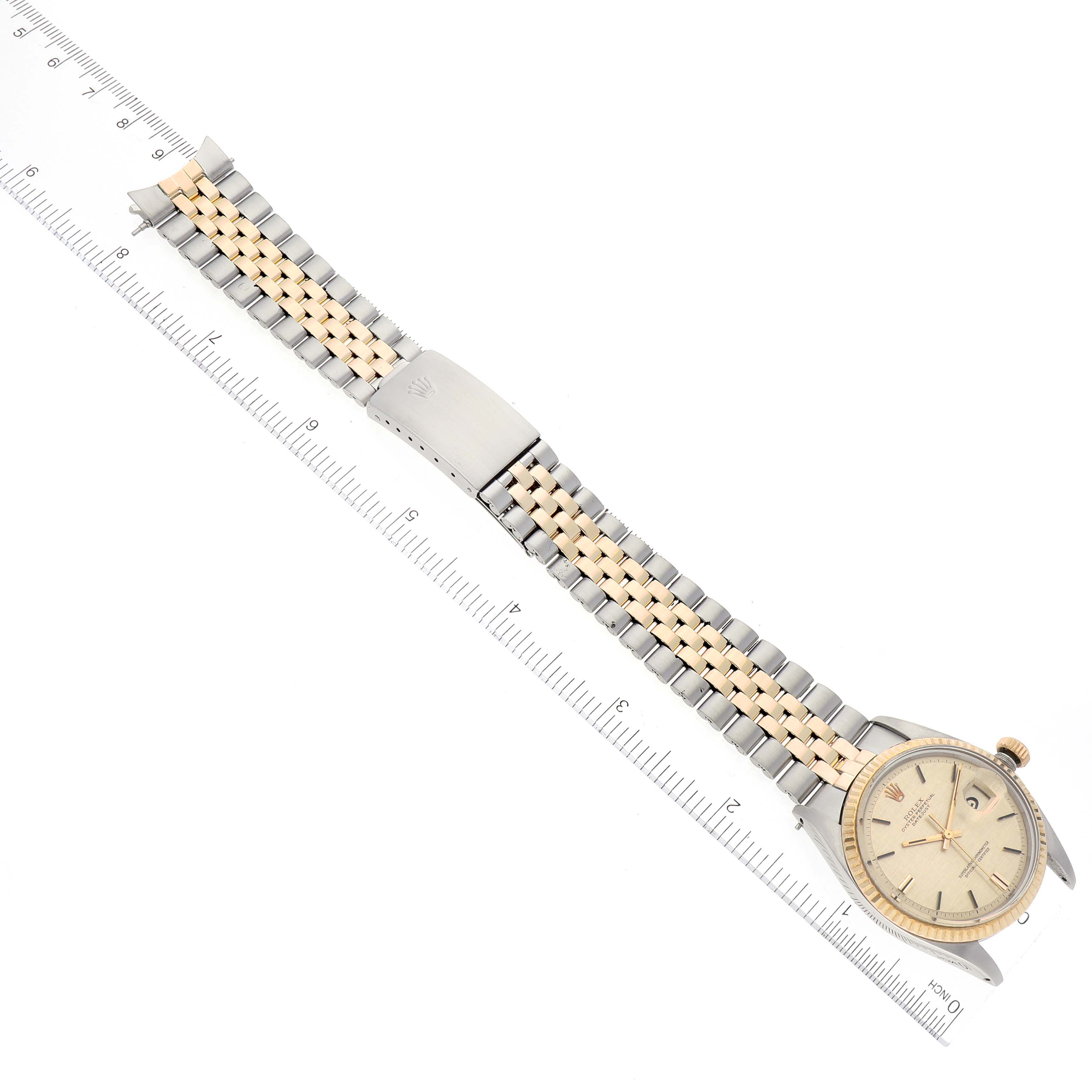 The image displays a Rolex Vintage Collection 1601 Men's Steel and Gold (two tone) Champagne Dial 1601 Men's Steel and Gold (two tone) Champagne Dial watch laid flat with a two-tone bracelet on a ruler for measurement.