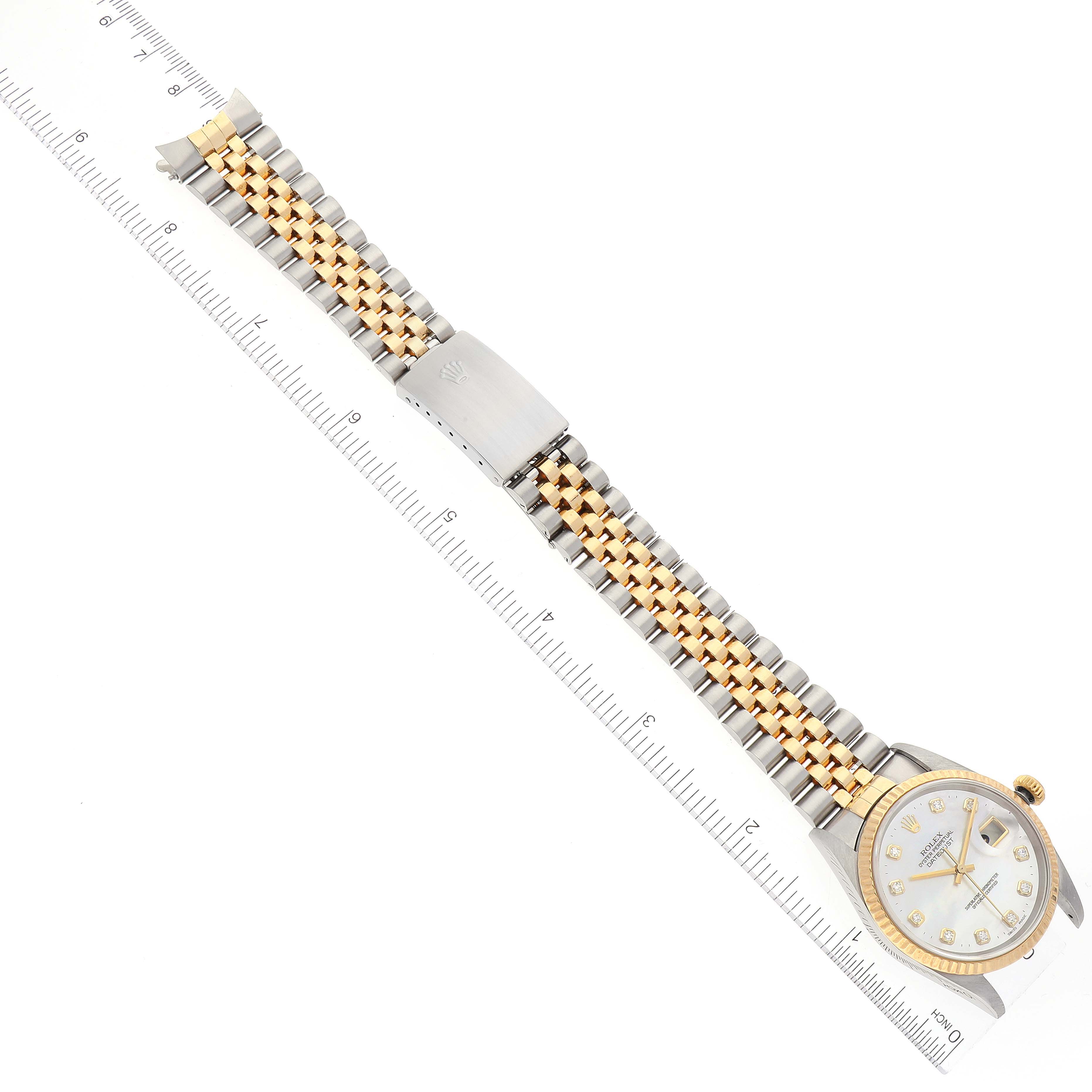 The image shows the Rolex Datejust 16233 Men's Steel and Gold (two tone) Mother of Pearl Dial 16233 Men's Steel and Gold (two tone) Mother of Pearl Dial watch laid flat with emphasis on its band and face, alongside a ruler for scale.
