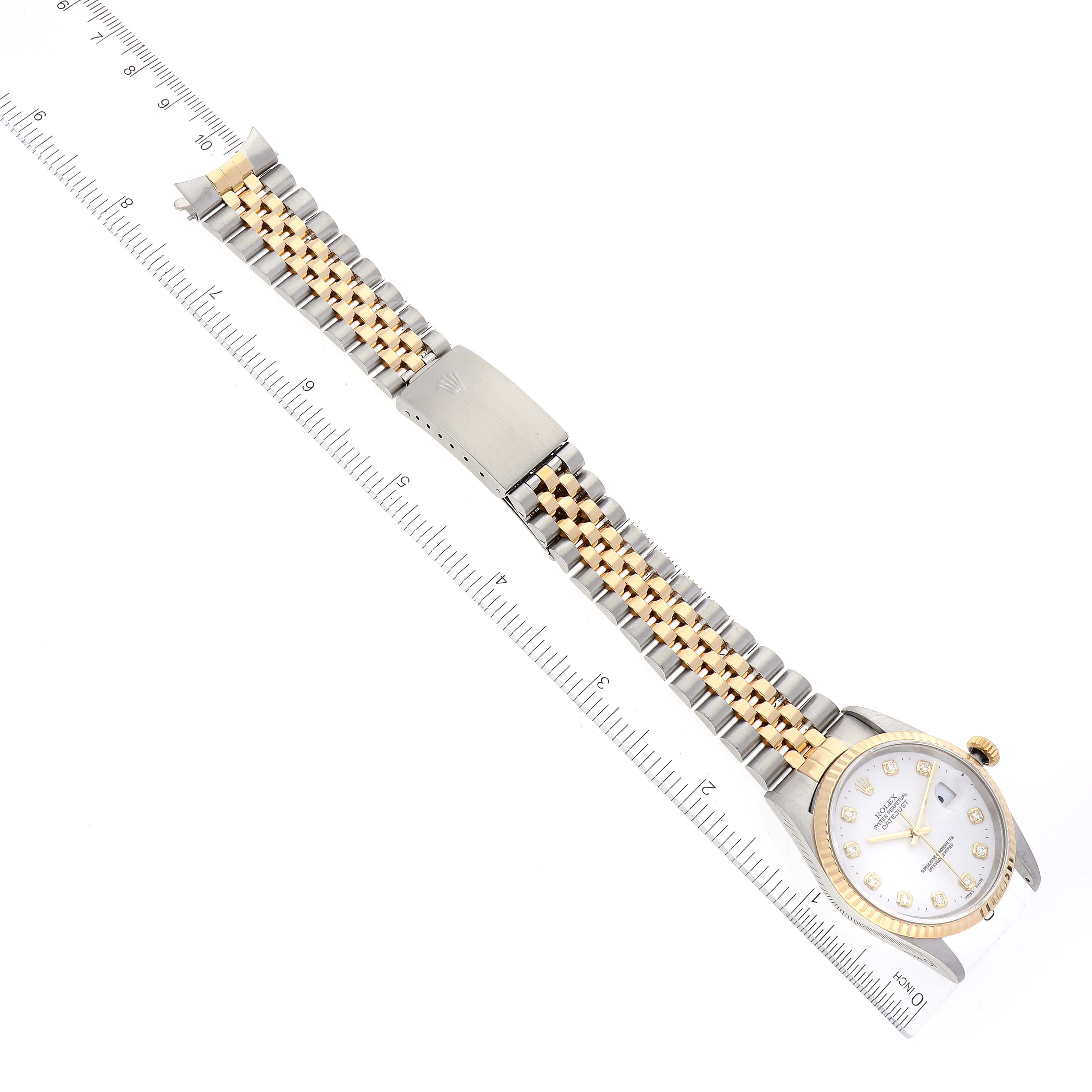 The Rolex Datejust 16233 Men's Steel and Gold (two tone) White Dial 16233 Men's Steel and Gold (two tone) White Dial watch is shown from a top-down angle, featuring its full bracelet and clasp, with a ruler for scale.