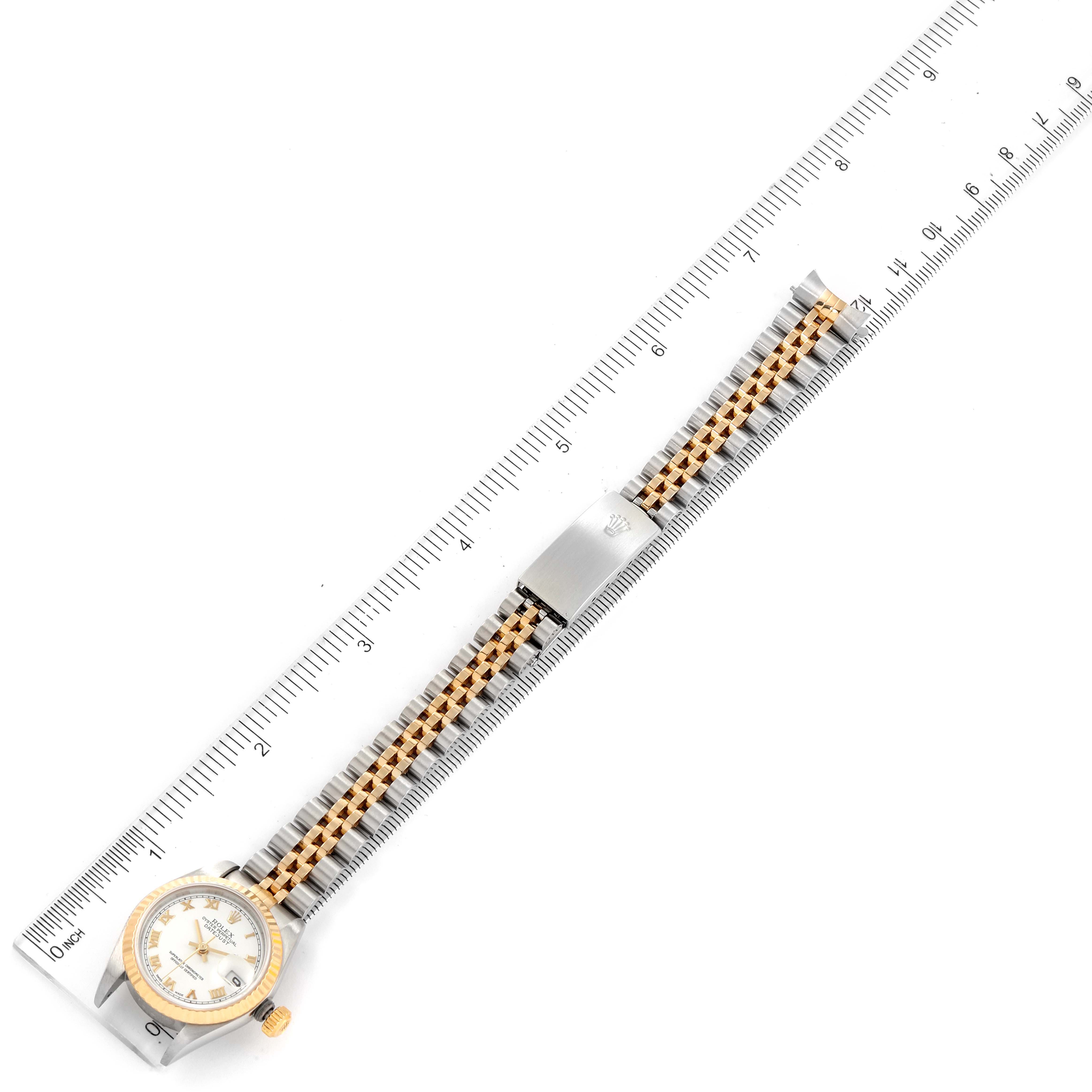 The Rolex Datejust 79173 Women's Steel and Gold (two tone) White Dial 79173 Women's Steel and Gold (two tone) White Dial watch is shown laid flat alongside a ruler, displaying the entire watch from face to clasp.
