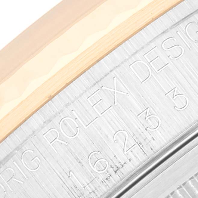 This macro shot of the Rolex Datejust 16233 Men's Steel and Gold (two tone) Champagne Dial 16233 Men's Steel and Gold (two tone) Champagne Dial model showcases the engraved side of the watch case and part of the bezel.