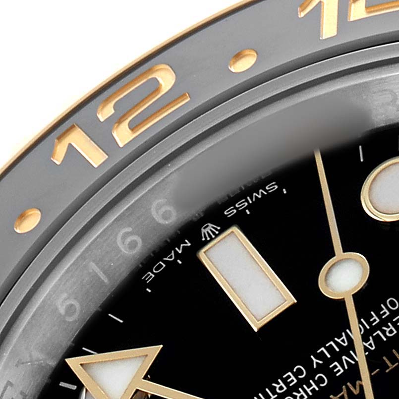 The image shows a close-up of the bezel and dial of a Rolex GMT-Master 126713 Men's Steel and Gold (two tone) Black Dial, highlighting the 12 marker and partial minute indices.