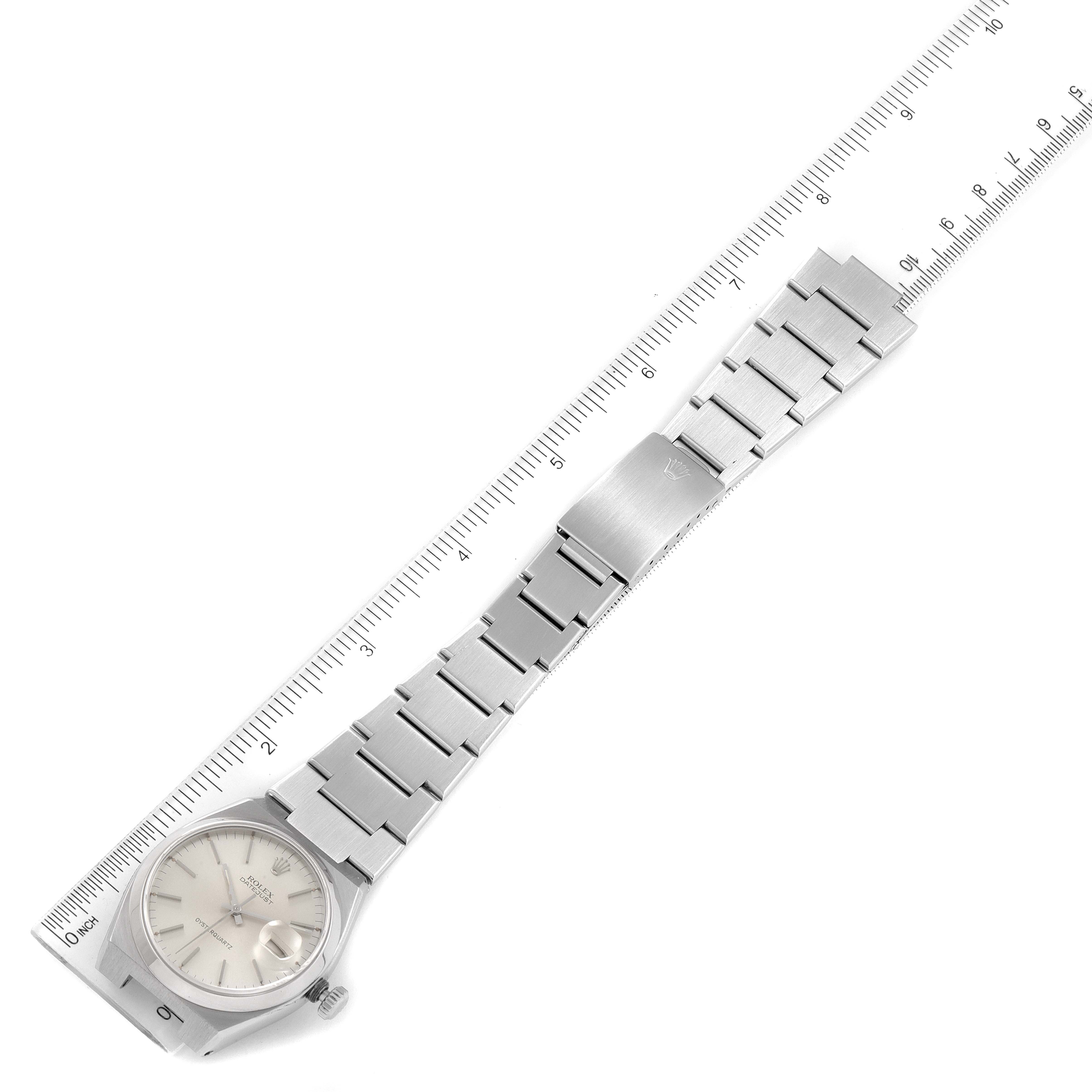 The image shows a top view of a Rolex Oysterquartz 17000 Men's Stainless Steel Silver Dial 17000 Men's Stainless Steel Silver Dial watch, with its face, bracelet, and clasp alongside a measuring ruler.