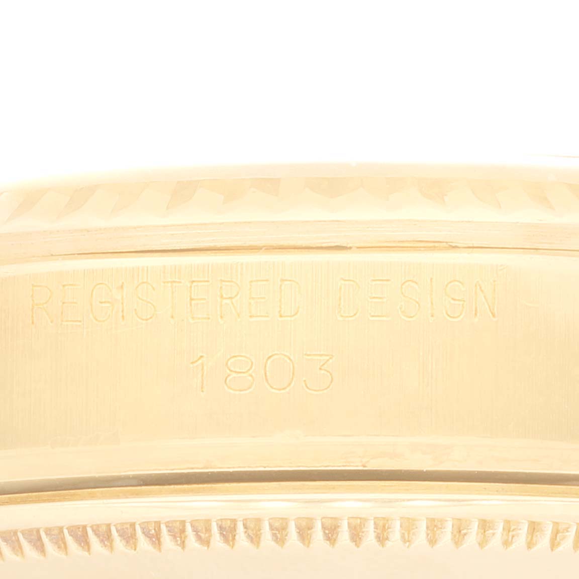 The image shows a close-up of the side of the Rolex Vintage Collection 1803 Men's Yellow Gold Champagne Dial 1803 Men's Yellow Gold Champagne Dial model, highlighting the "Registered Design 1803" engraving.