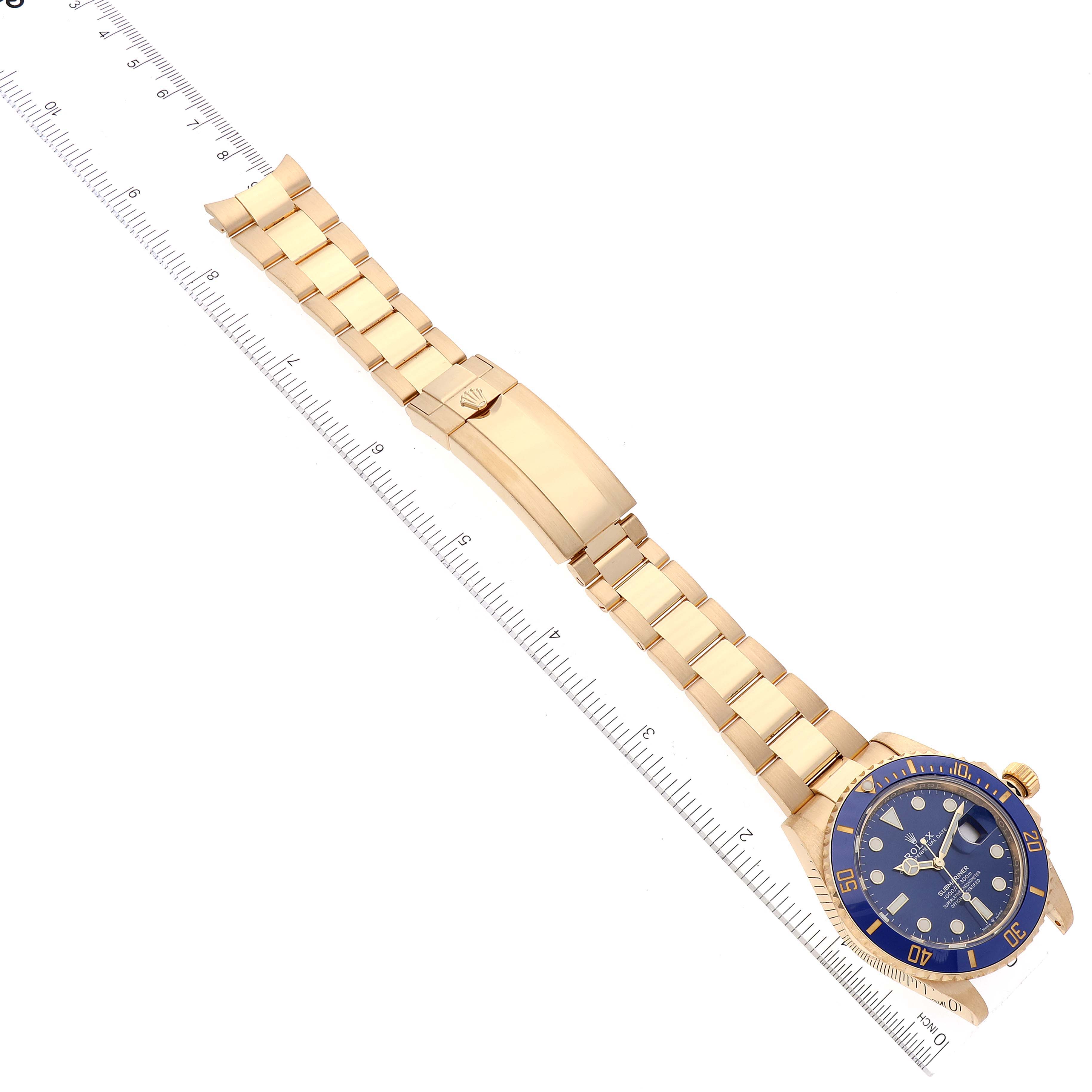 The Rolex Submariner 126618 Men's Yellow Gold Blue Dial 126618 Men's Yellow Gold Blue Dial watch is displayed flat, showcasing its full gold bracelet and blue dial, alongside a measuring ruler.