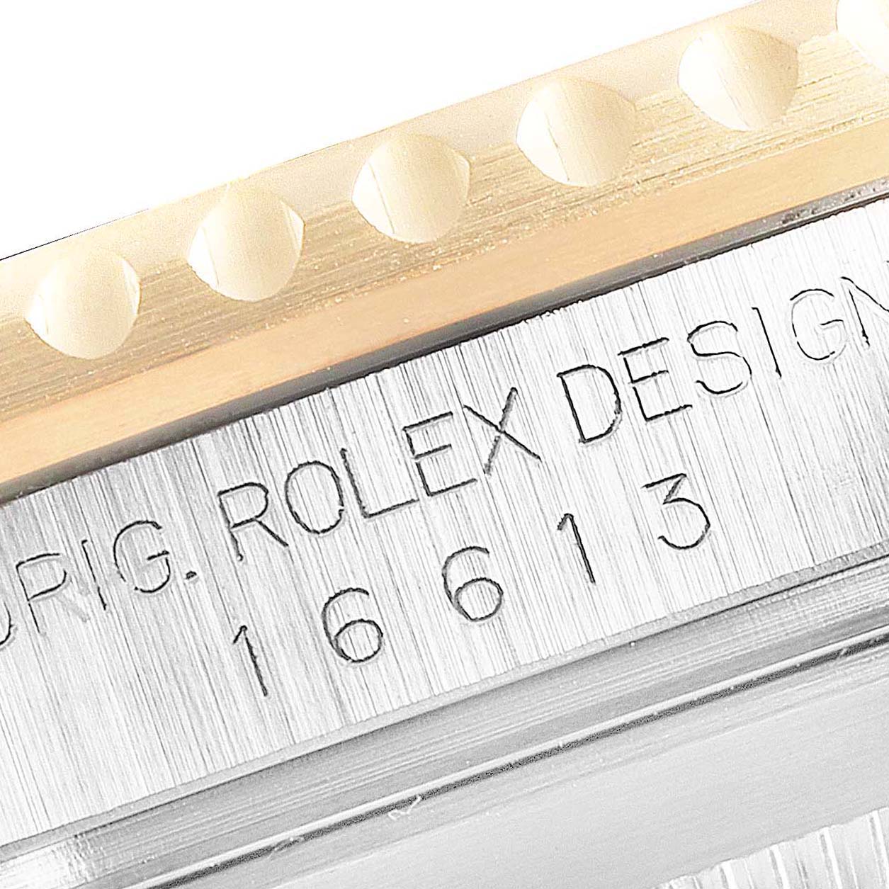 The image shows a close-up of the engraved side of the case and part of the bezel of a Rolex Submariner 16613 Men's Steel and Gold (two tone) Blue Dial 16613 Men's Steel and Gold (two tone) Blue Dial model.