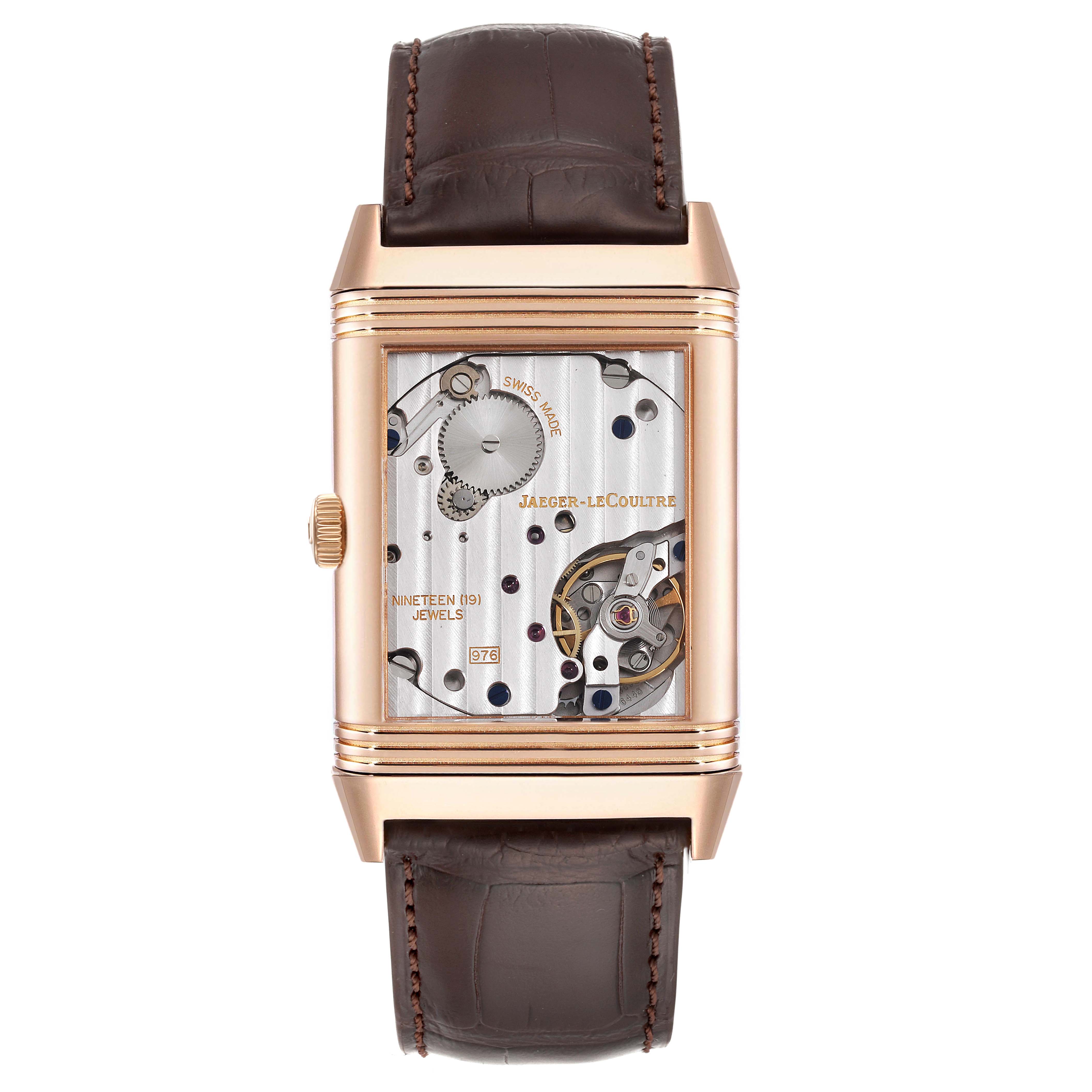 The Jaeger-LeCoultre Reverso model is shown from the front, displaying its exposed mechanical movement inside a rectangular case.