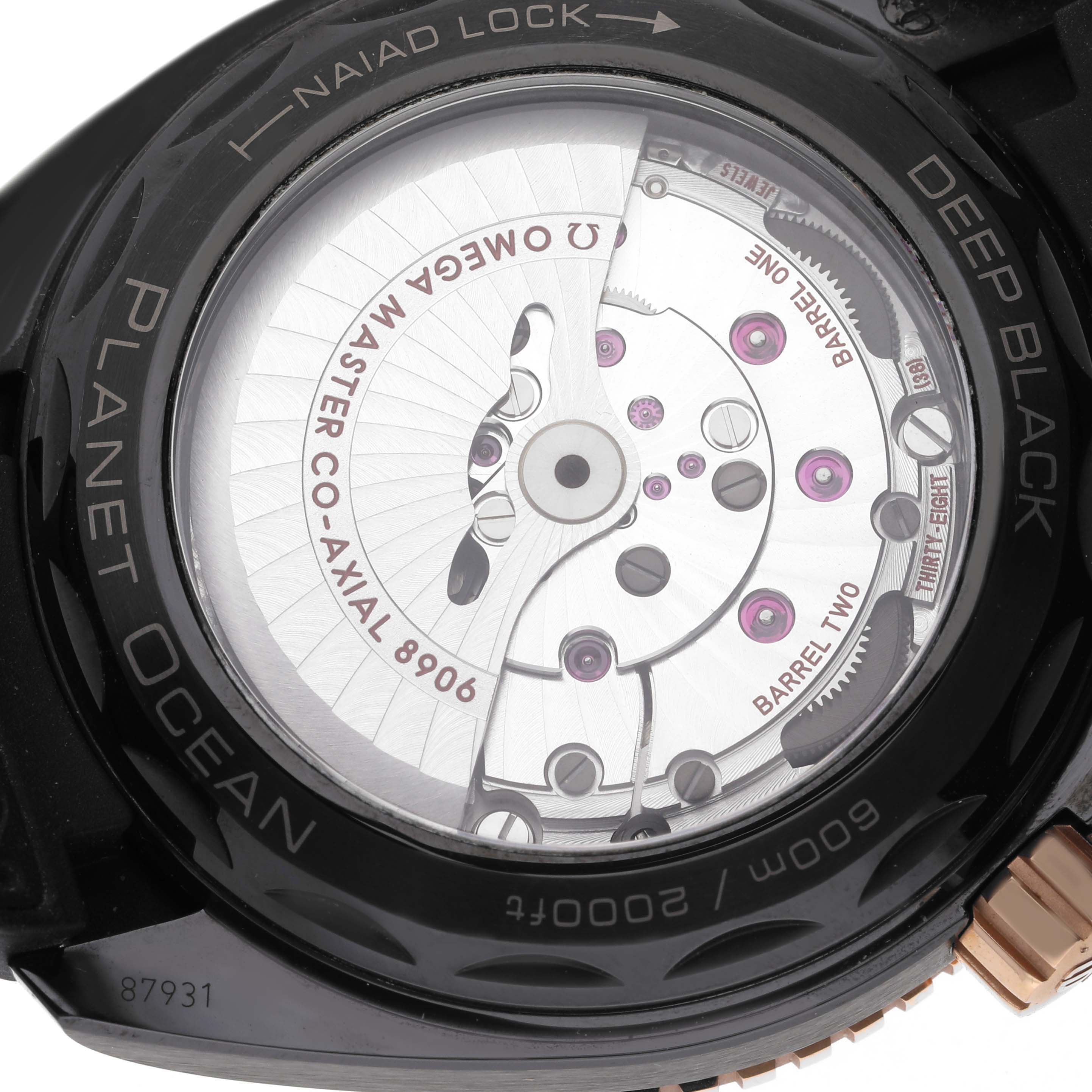 The image shows a close-up view of the back of an Omega Planet Ocean 215.63.46.22.01.001 Men's Ceramic Black Dial 215.63.46.22.01.001 Men's Ceramic Black Dial watch, highlighting the movement and inscriptions.