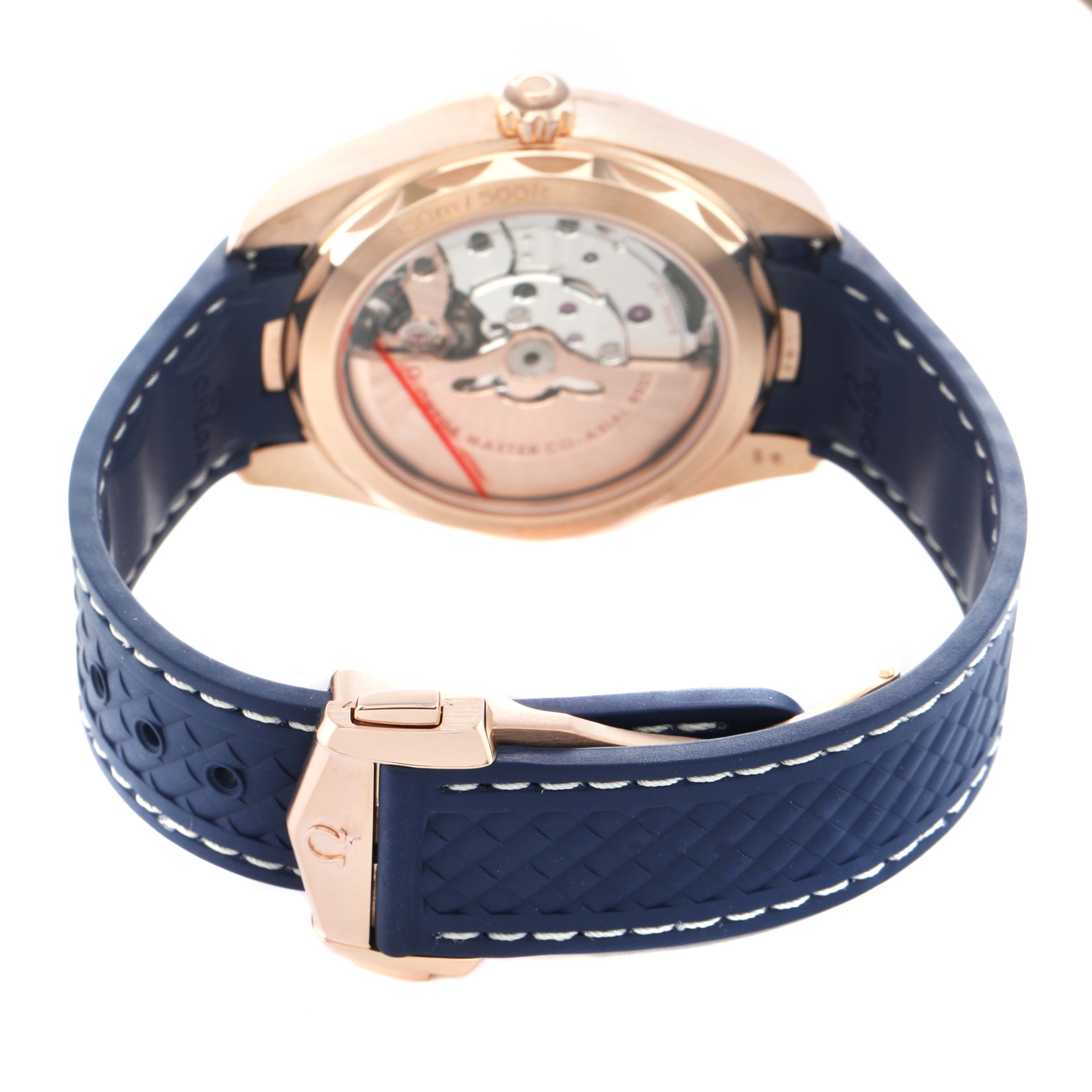 The Omega Aqua Terra 220.52.41.21.03.001 Men's Rose Gold Blue Dial watch is shown from the back, highlighting its open case back, gears, and blue strap with a deployment clasp.