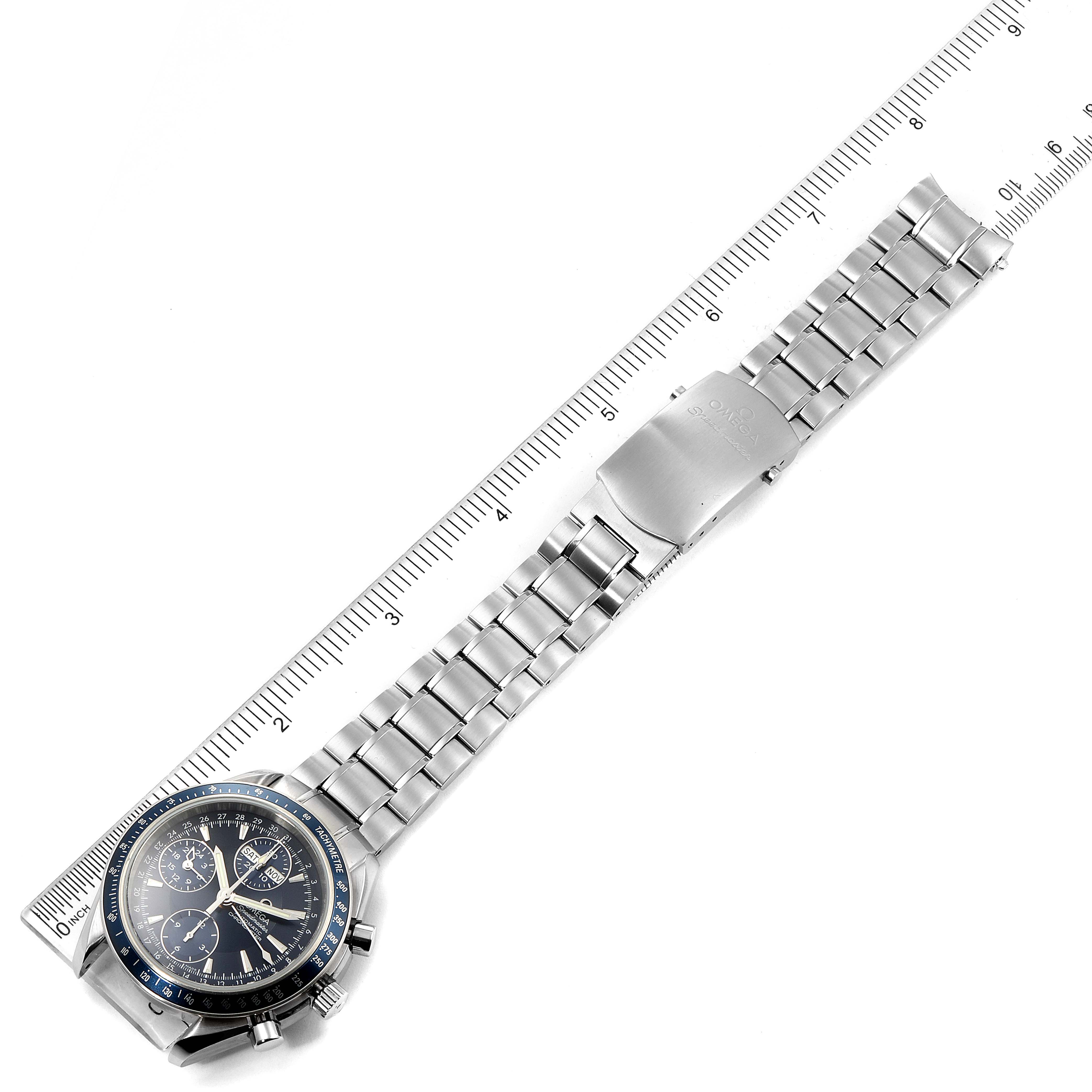 The image shows an Omega Speedmaster 3222.80.00 Men
s Stainless Steel Blue Dial 3222.80.00 Men
s Stainless Steel Blue Dial watch laid flat with its face, bezel, and metal bracelet visible, beside a ruler for scale.