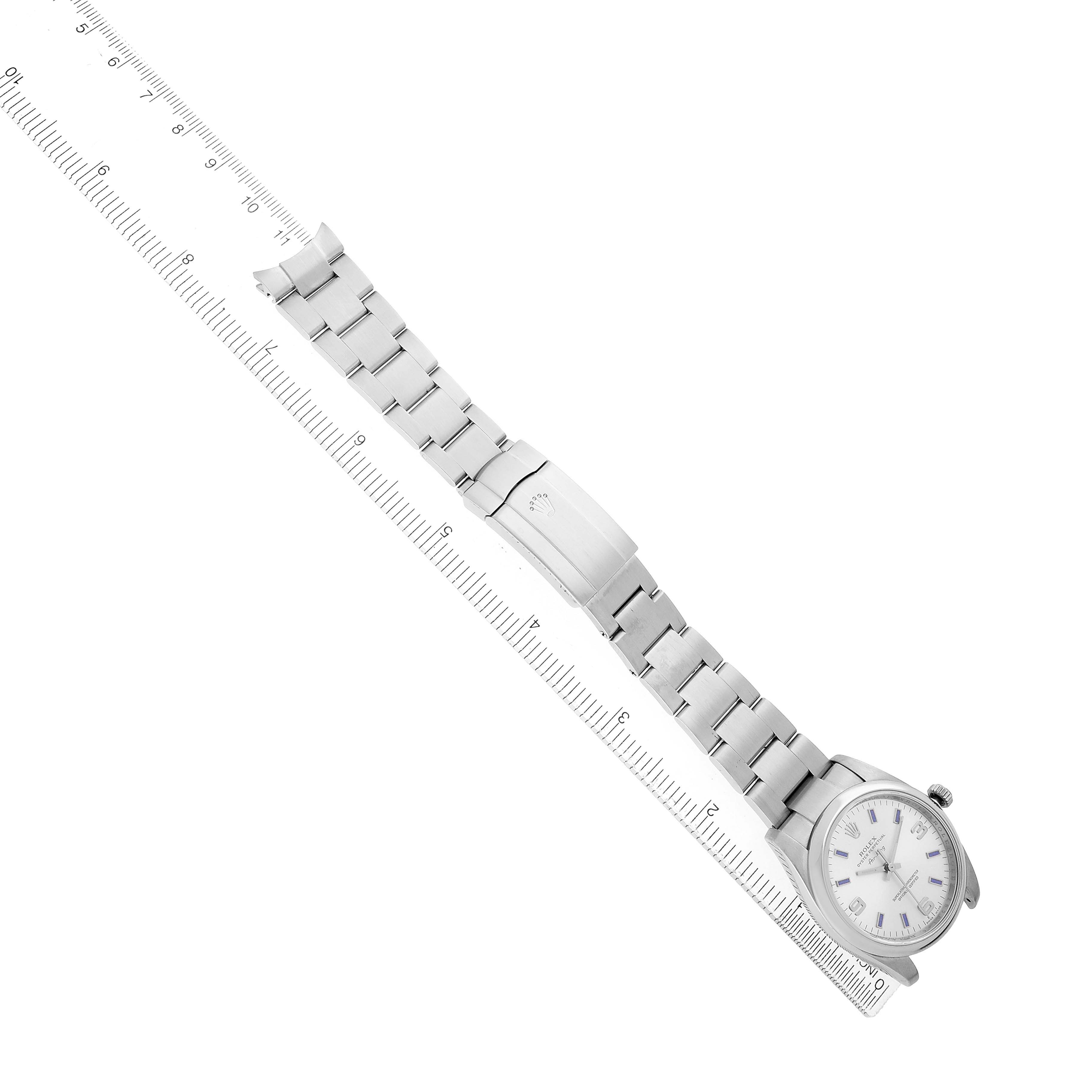 The Rolex Air-King 114200 Men's Stainless Steel Silver Dial watch is shown from a top-down angle, featuring its full bracelet alongside a ruler for scale.